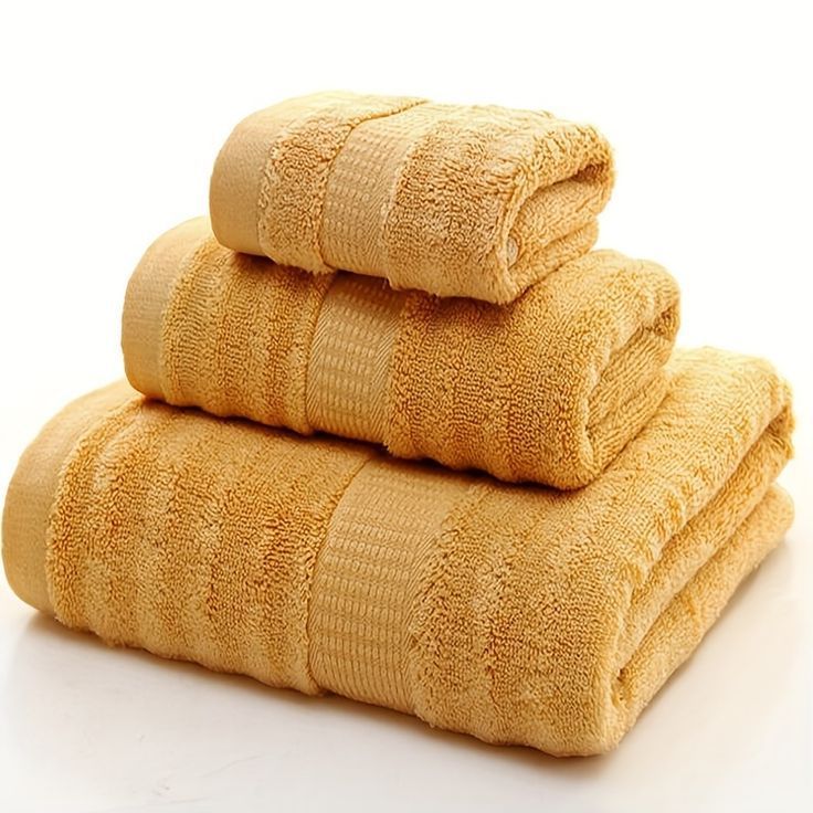 Trois serviettes jaunes sont empilées les unes sur les autres sur une surface blanche