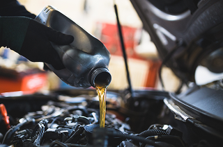 Mechanic pouring oil into engine of vehicle for oil change | Iberia Discount Tire