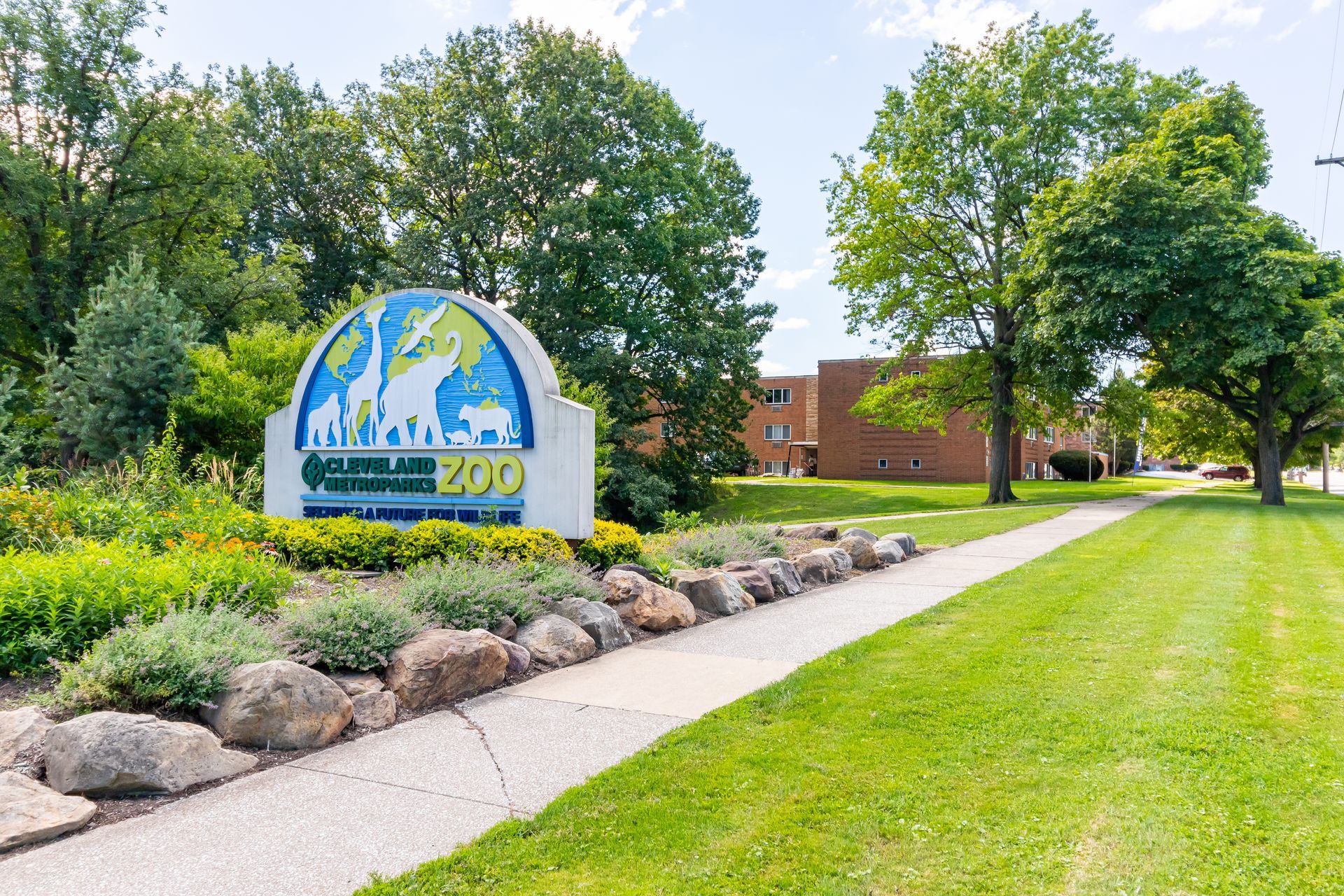 Sign for Columbus Zoo and Aquarium with a sidewalk and green space.