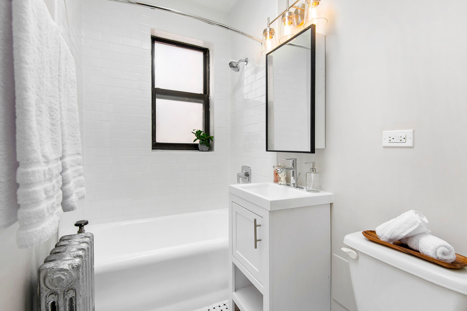 A bathroom with a tub, sink, mirror, and window at Reside at Belmont Harbor. 