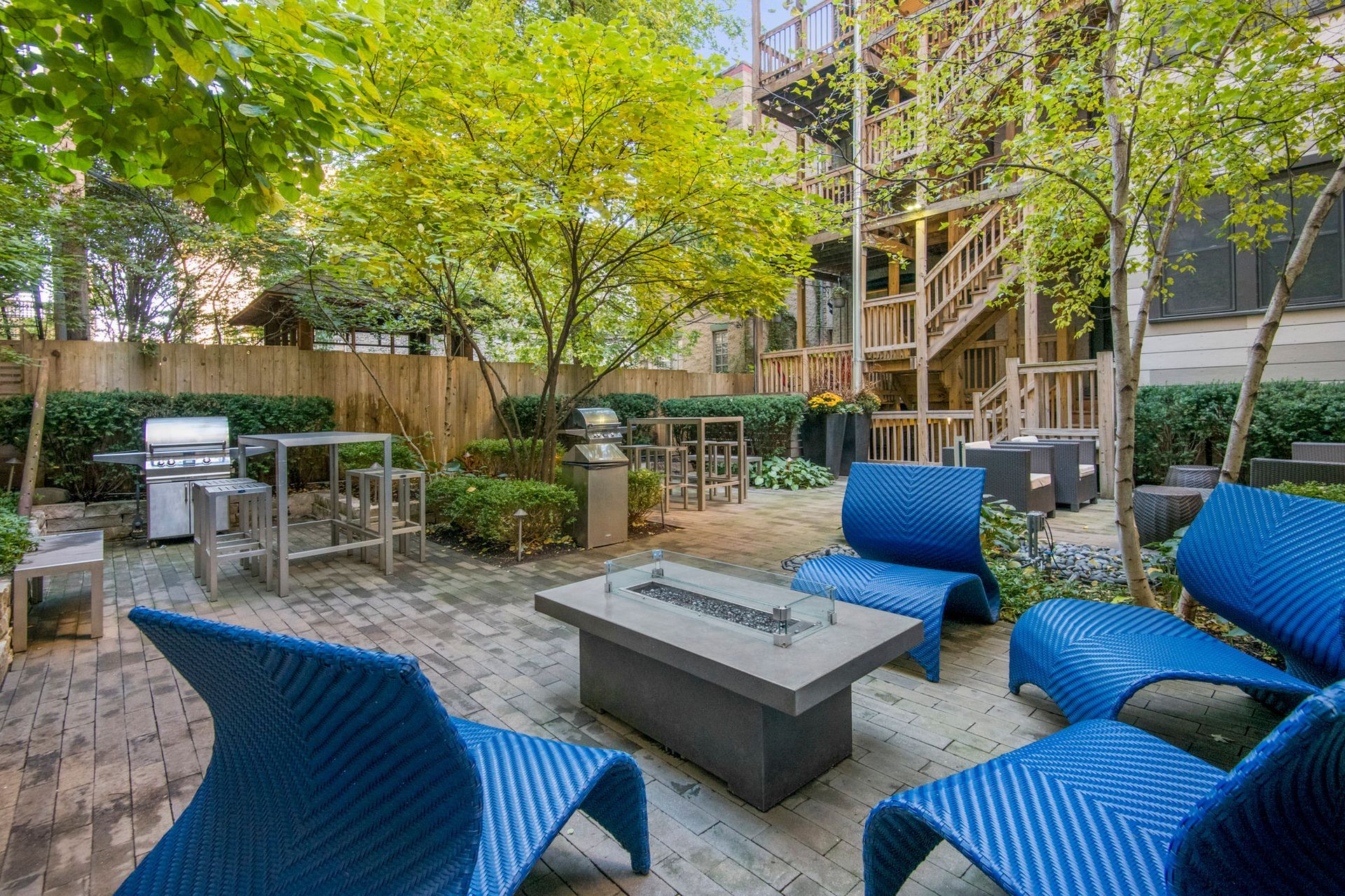 A patio with blue chairs, a table, and a grill at Reside at Belmont Harbor. 