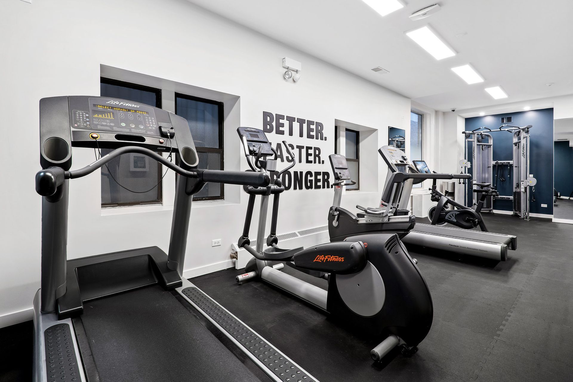 A gym with a sign on the wall that says better faster stronger at Reside at Belmont Harbor. 