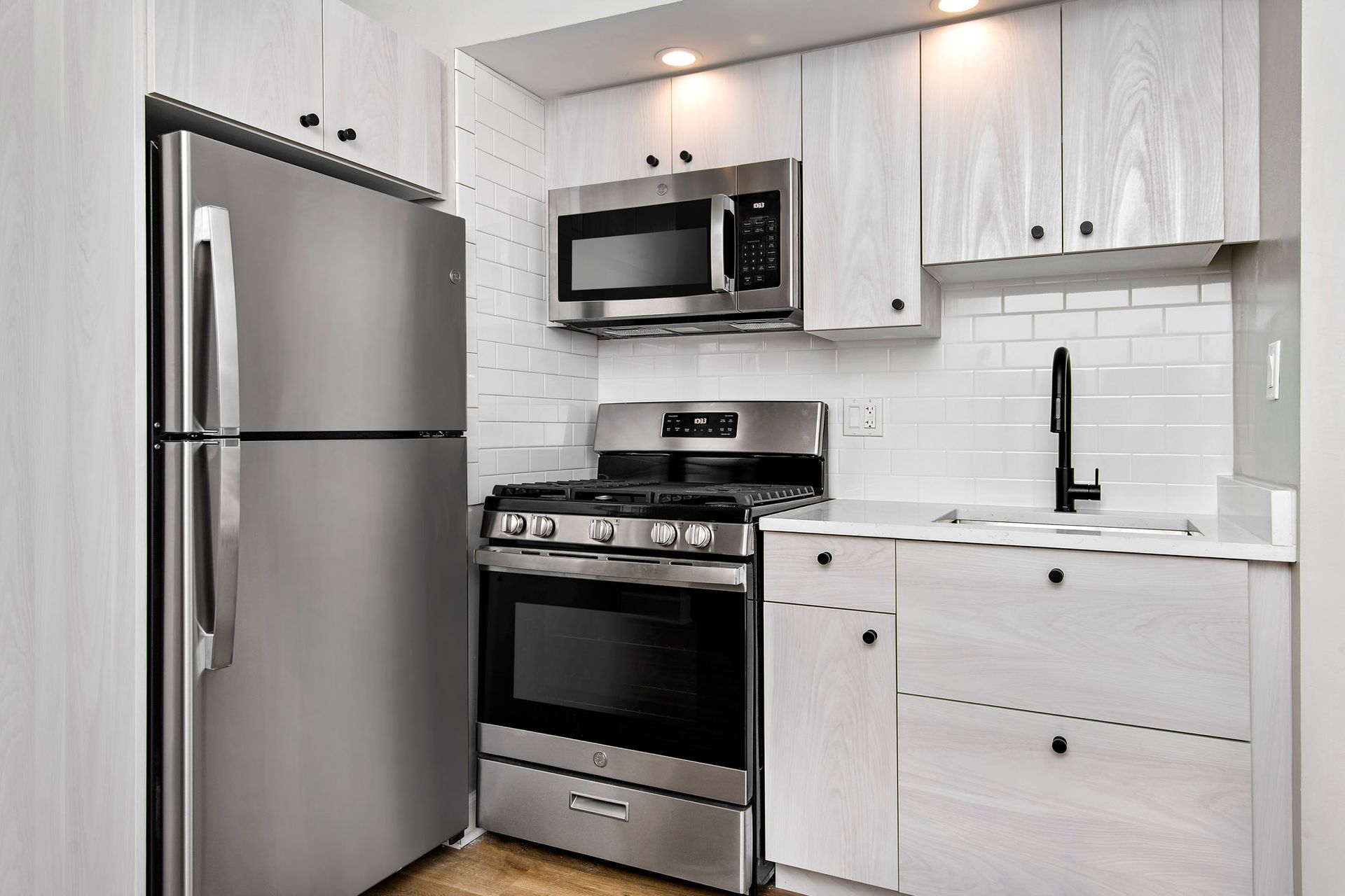 A kitchen with stainless steel appliances and white cabinets at Reside at Belmont Harbor. 