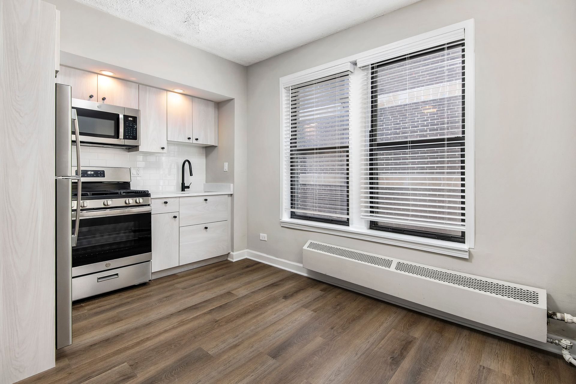 A kitchen with a refrigerator, stove, microwave, and two windows at Reside at Belmont Harbor. 