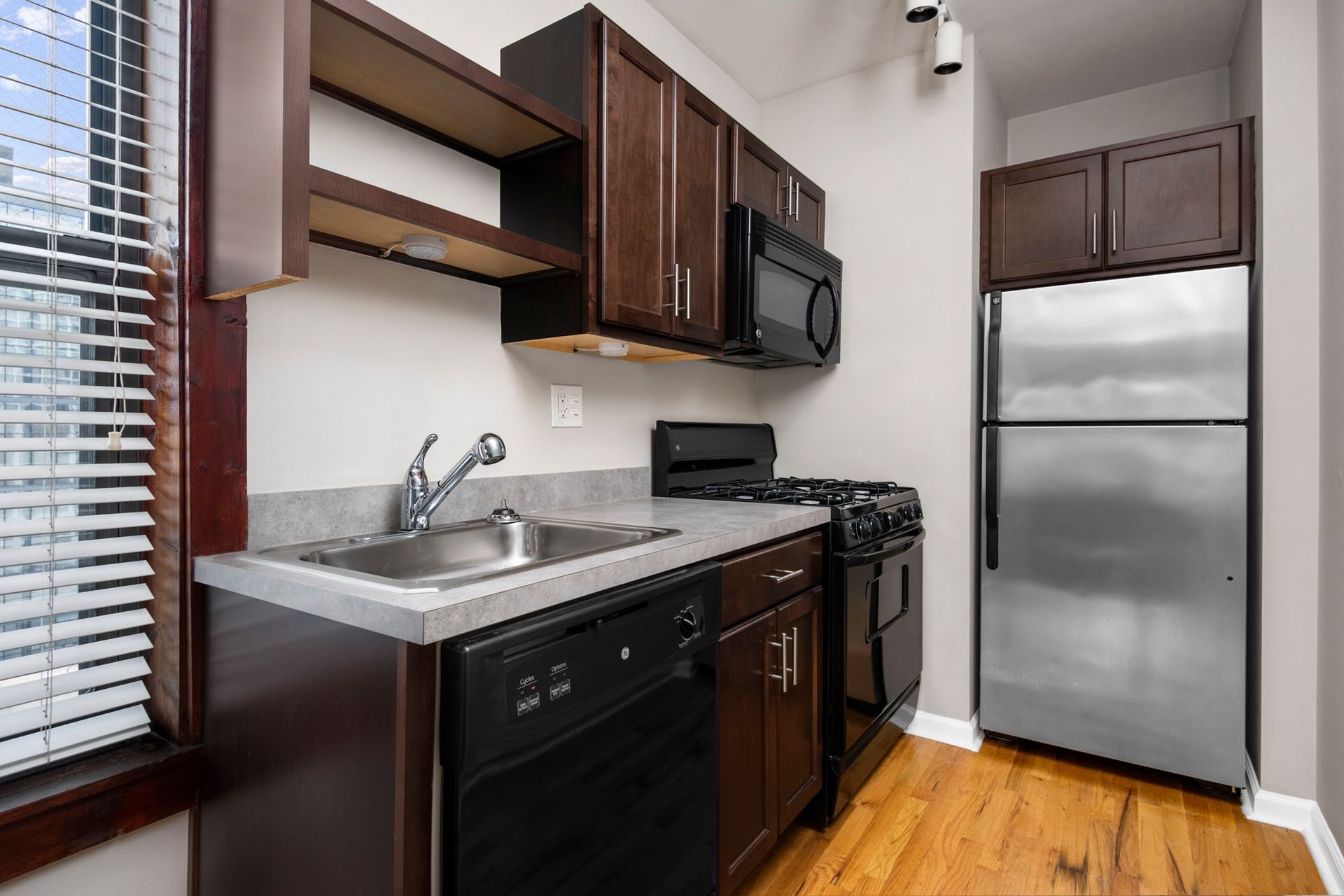 A kitchen with stainless steel appliances and wooden floors at Reside at Belmont Harbor. 
