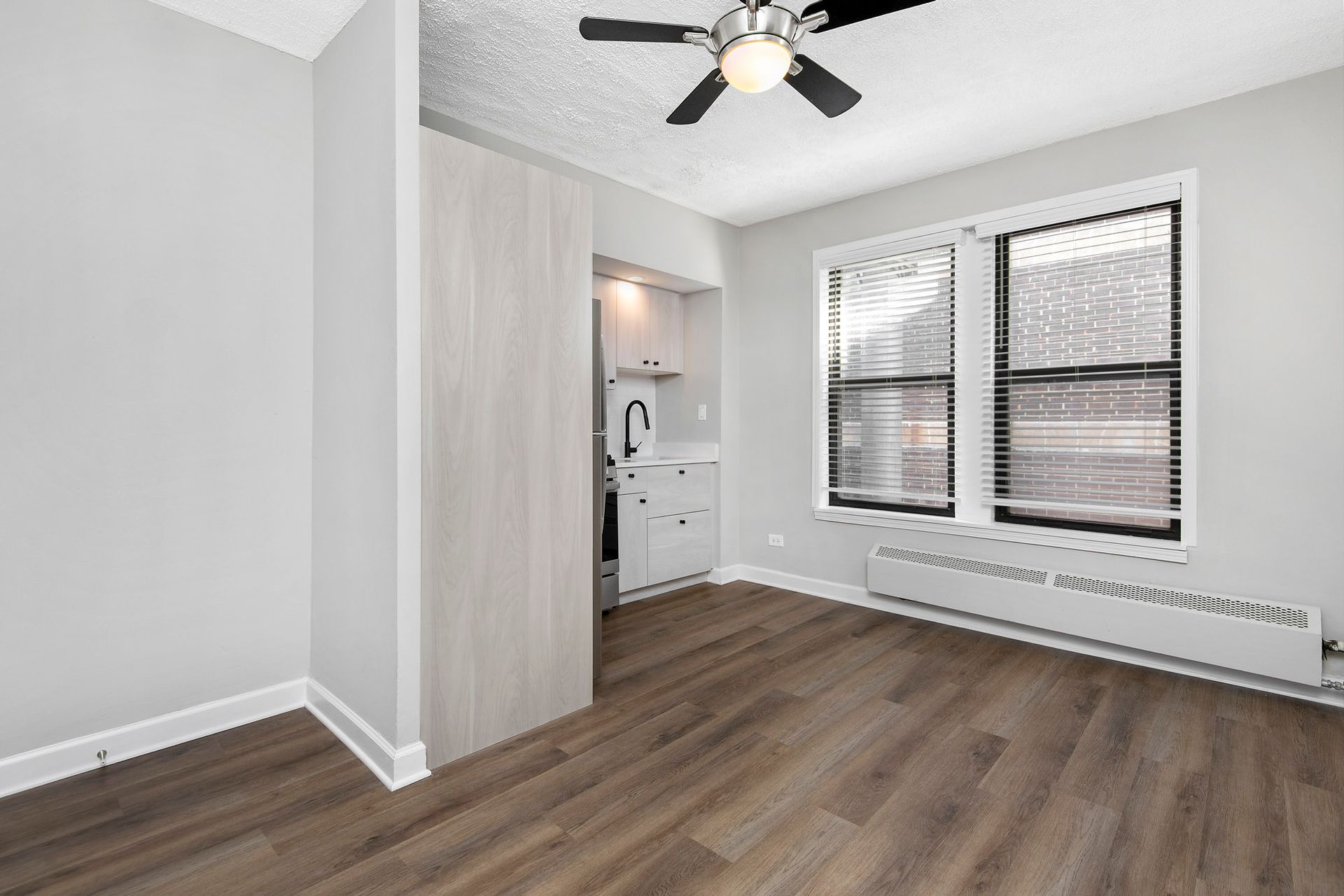 An empty room with hardwood floors and a ceiling fan at Reside at Belmont Harbor. 