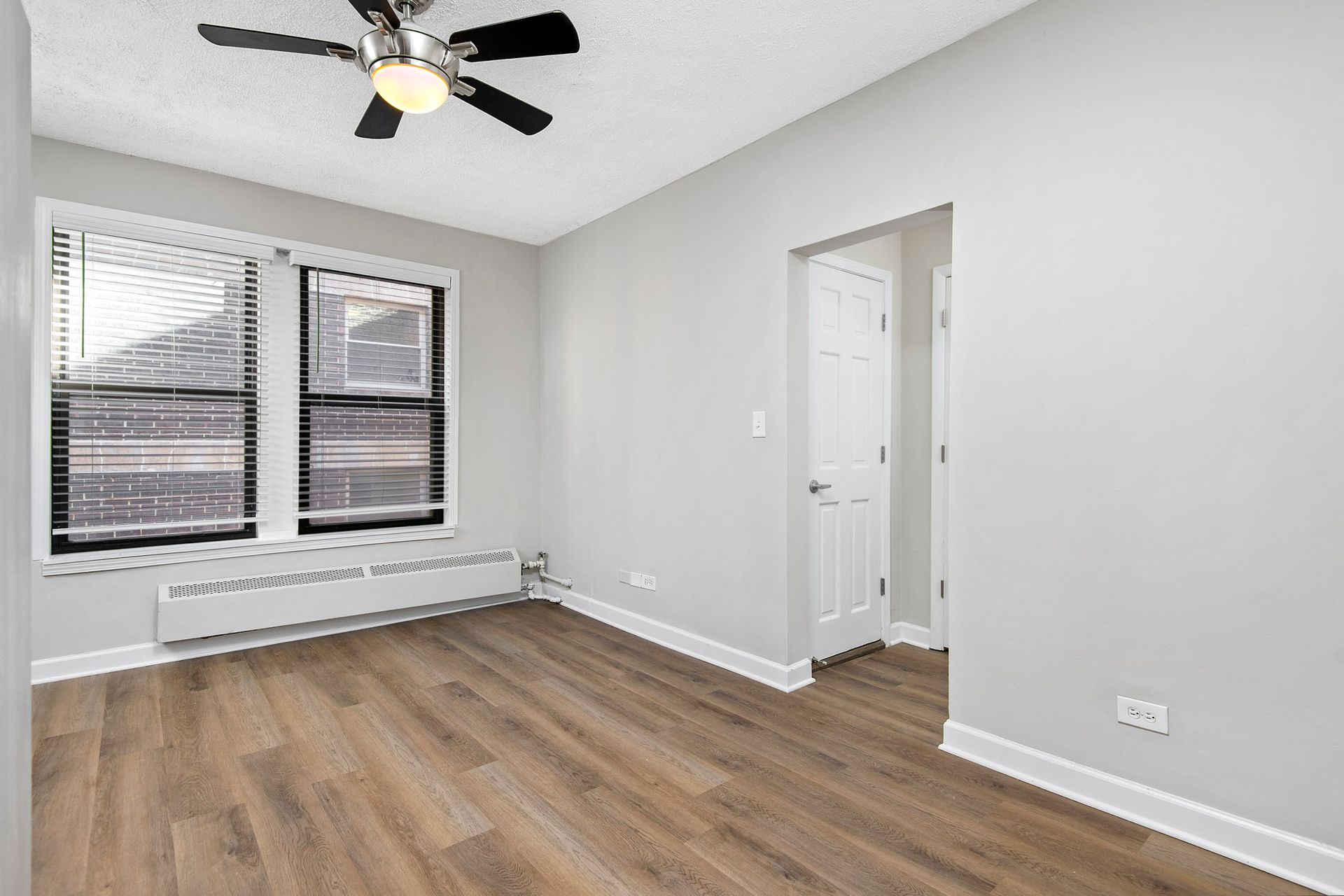An empty room with hardwood floors and a ceiling fan at Reside at Belmont Harbor. 