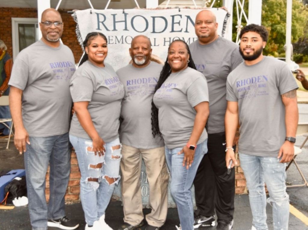 Group of six people in grey shirts, standing in front of