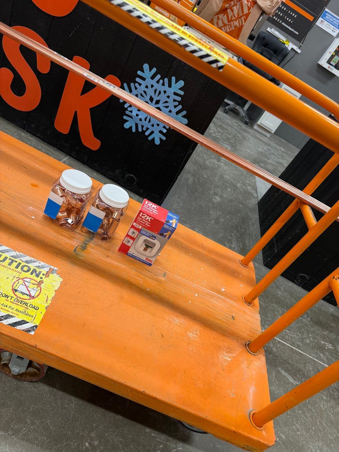 Orange platform with three small items on it and a black sign with snowflakes in the background