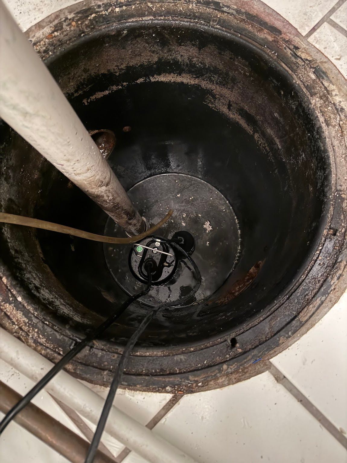 Inside a dirty black bucket, with a white pole and cables, viewed from above