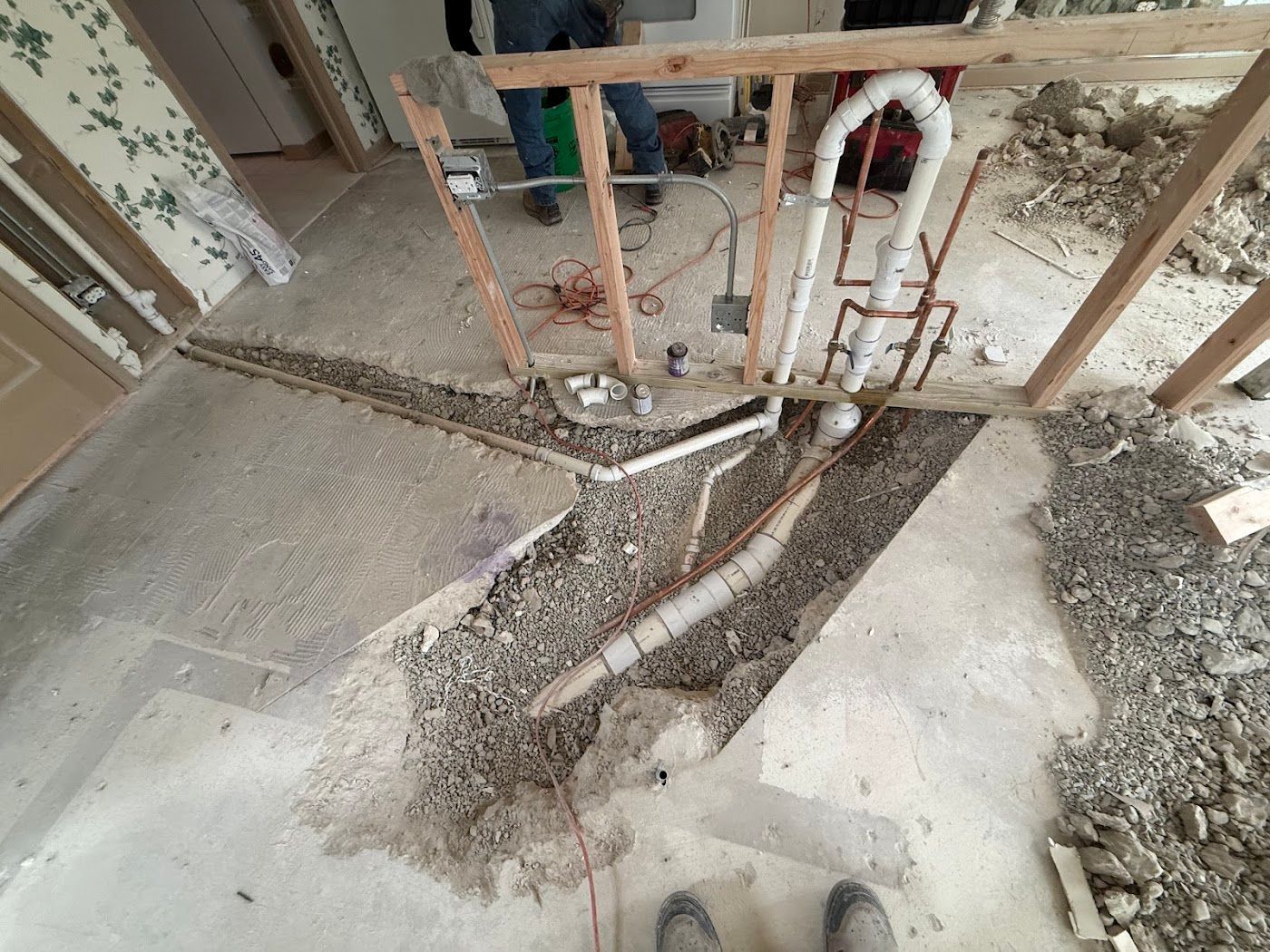 Cement slab with a large trench exposing pipes and rebar at an indoor construction site