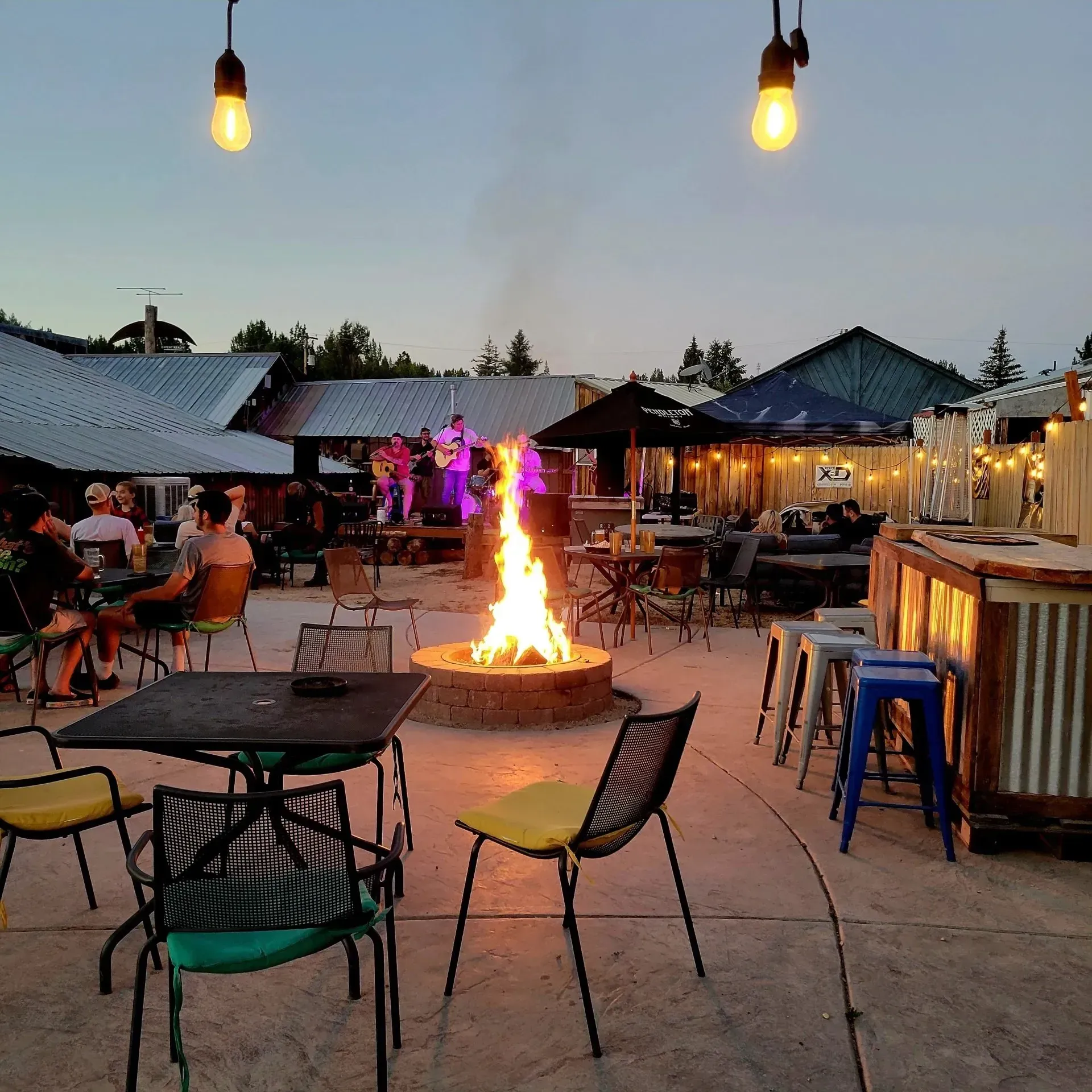 A fire pit is surrounded by tables and chairs