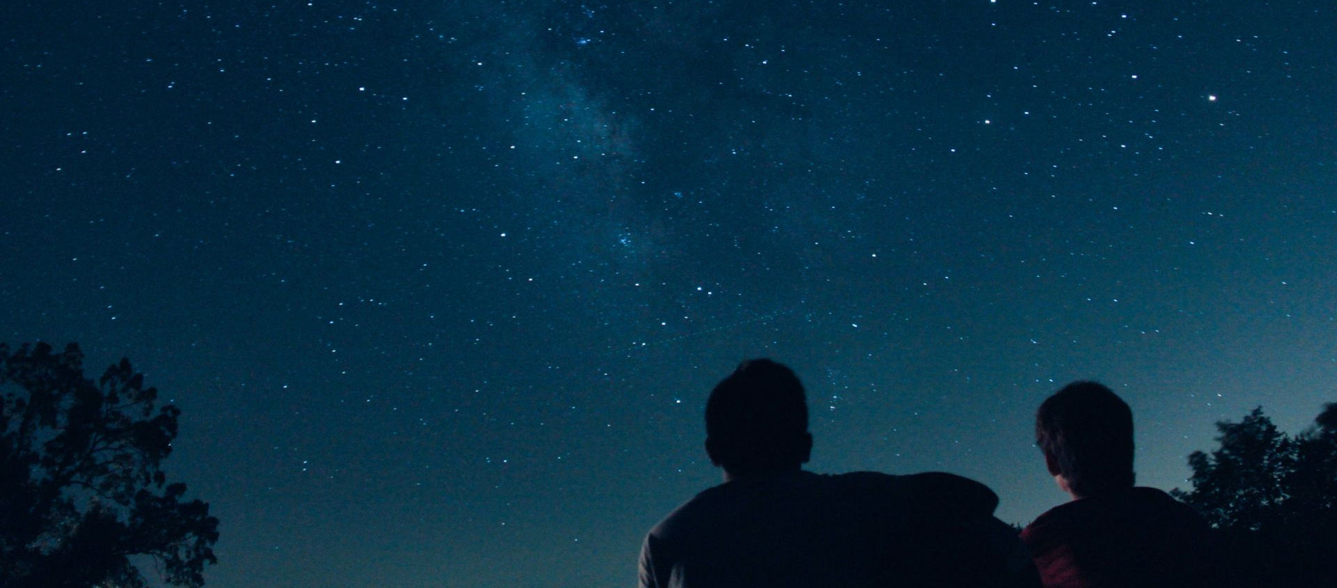 Two people looking up at a starry night sky.