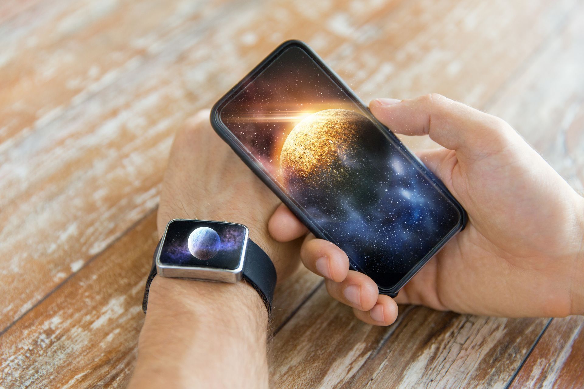 Person holding phone and wearing smartwatch, both displaying starry galaxy images.