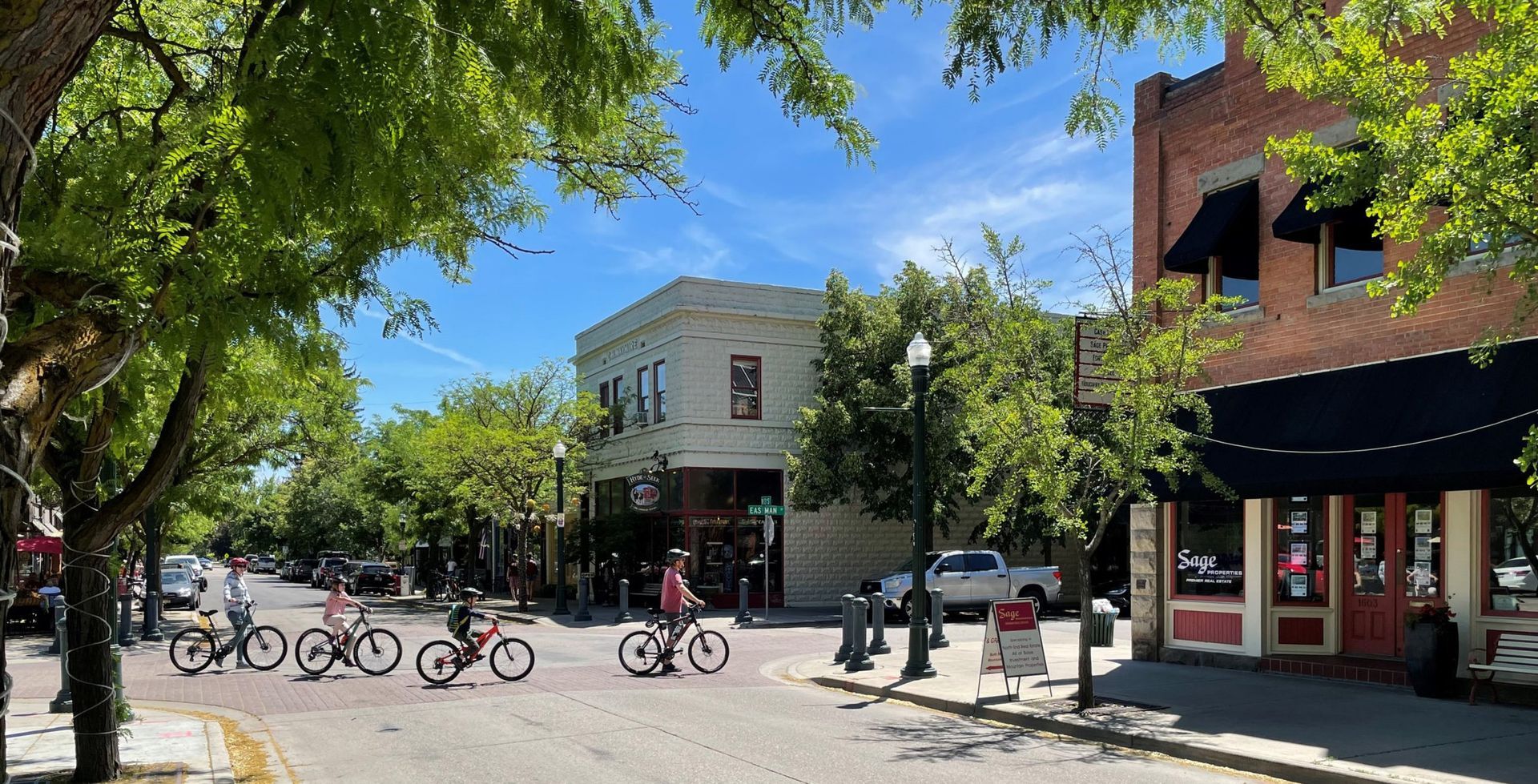 Street scene with cyclists, trees, buildings, and a clear blue sky.