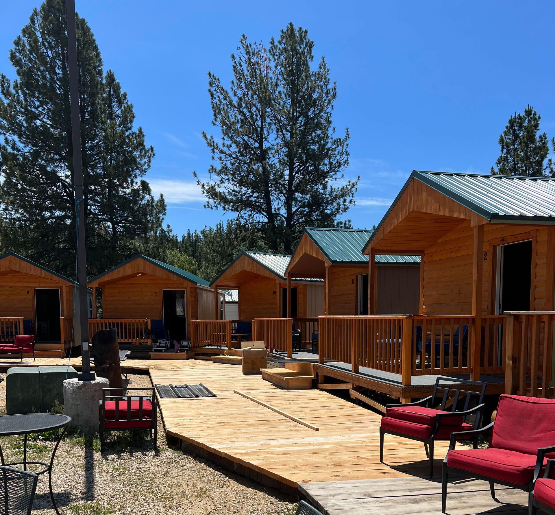 A row of wooden cabins with red chairs and tables