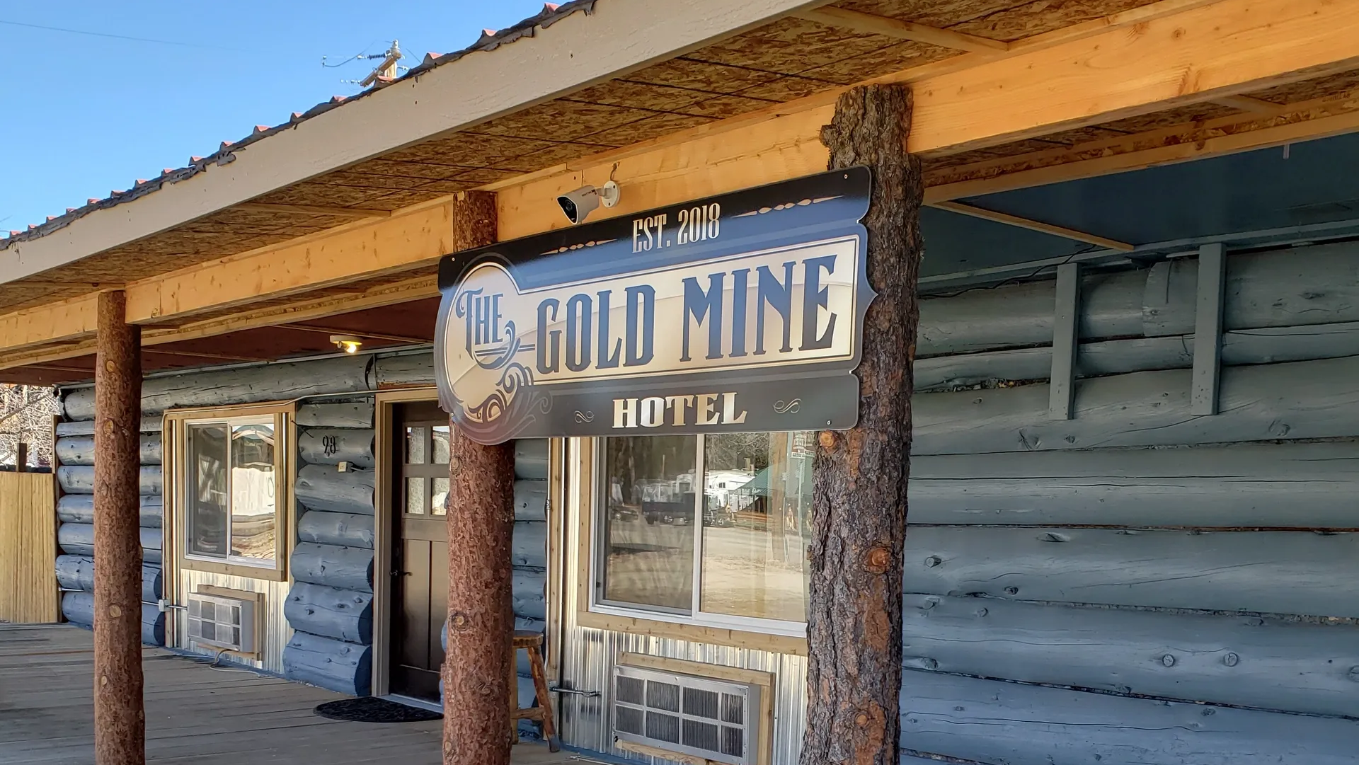Rustic wooden facade of the Gold Mine Hotel with a hanging sign and porch windows