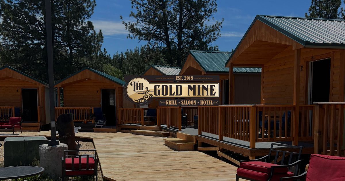 Cabins at the Big Gold Mine. Wooden cabins with green roofs and porches, outdoor seating.