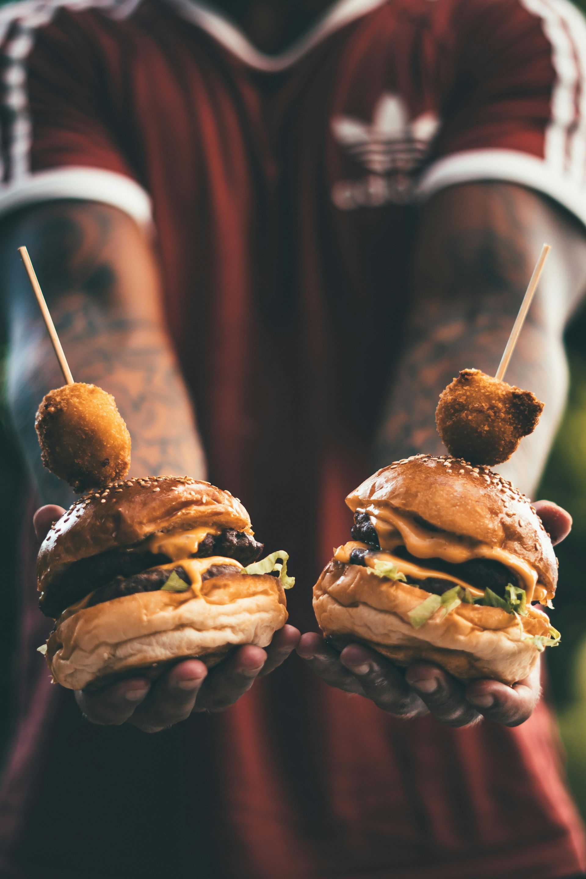 A man is holding two hamburgers in his hands.
