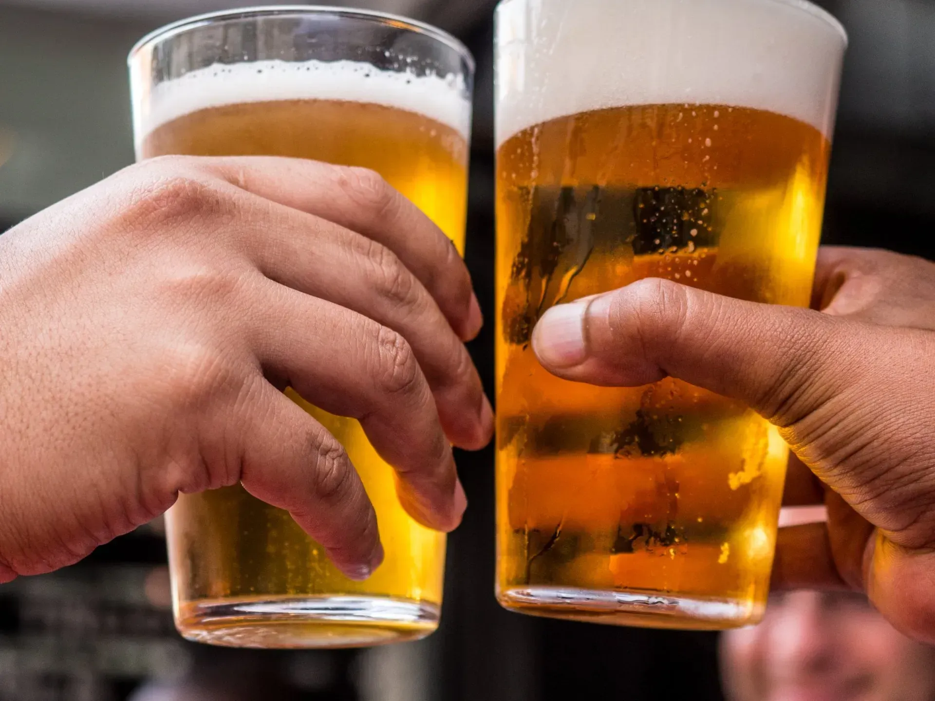 Two people are toasting with two glasses of beer.