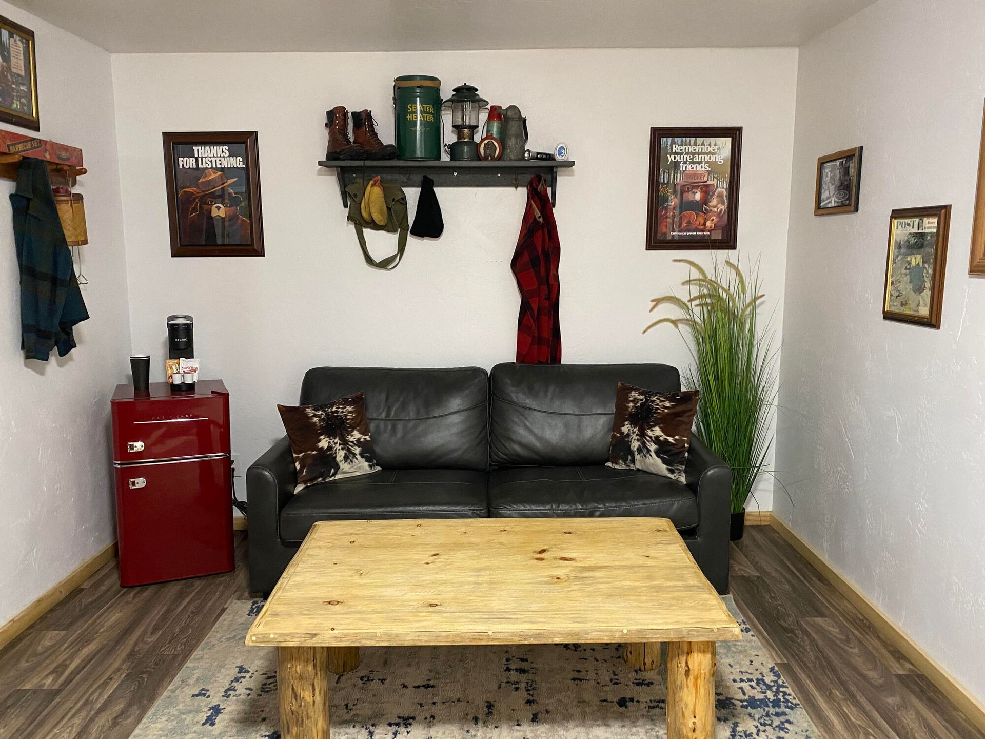 A living room with a couch , coffee table , and refrigerator.