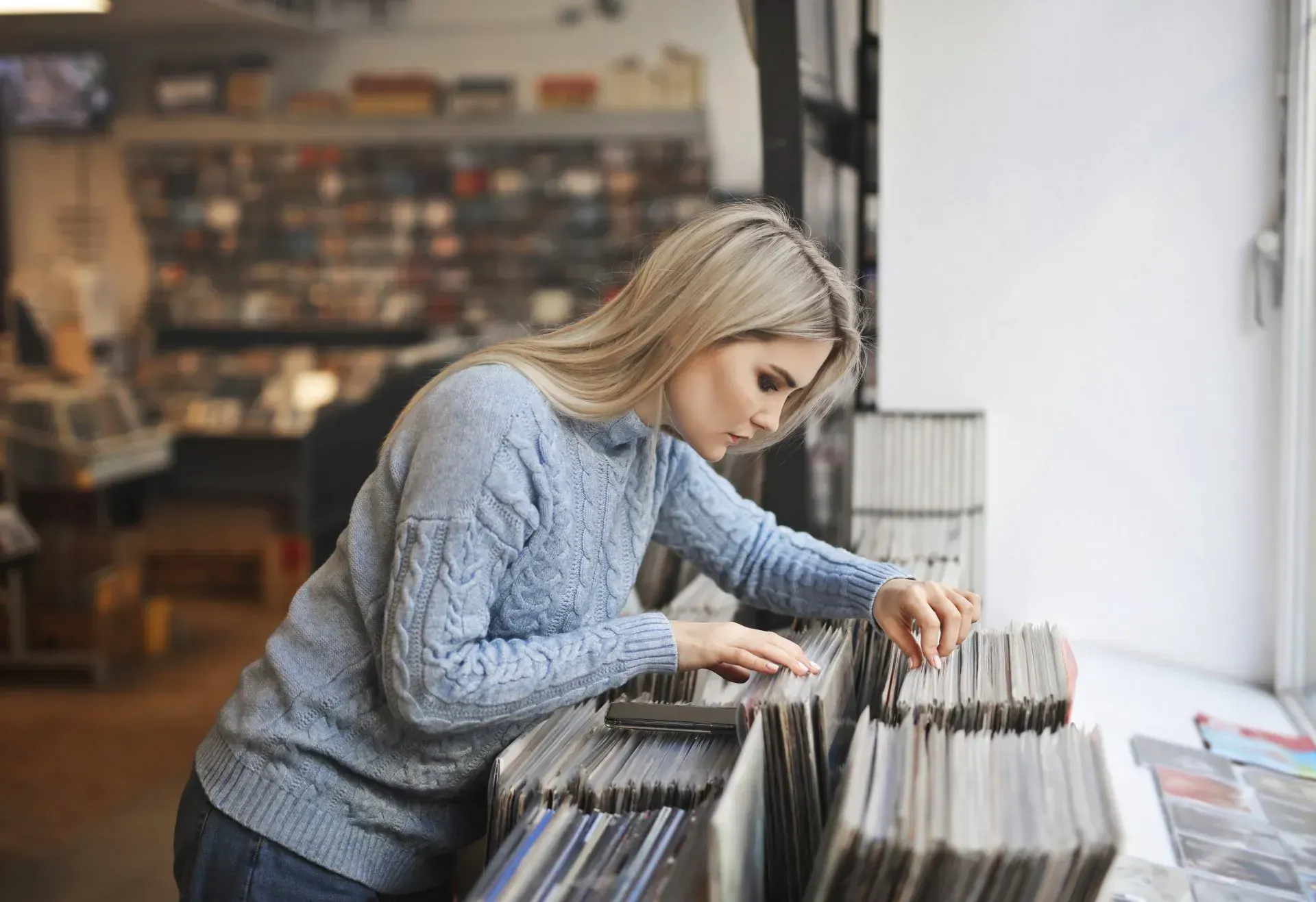 A woman is looking at records in a record store.