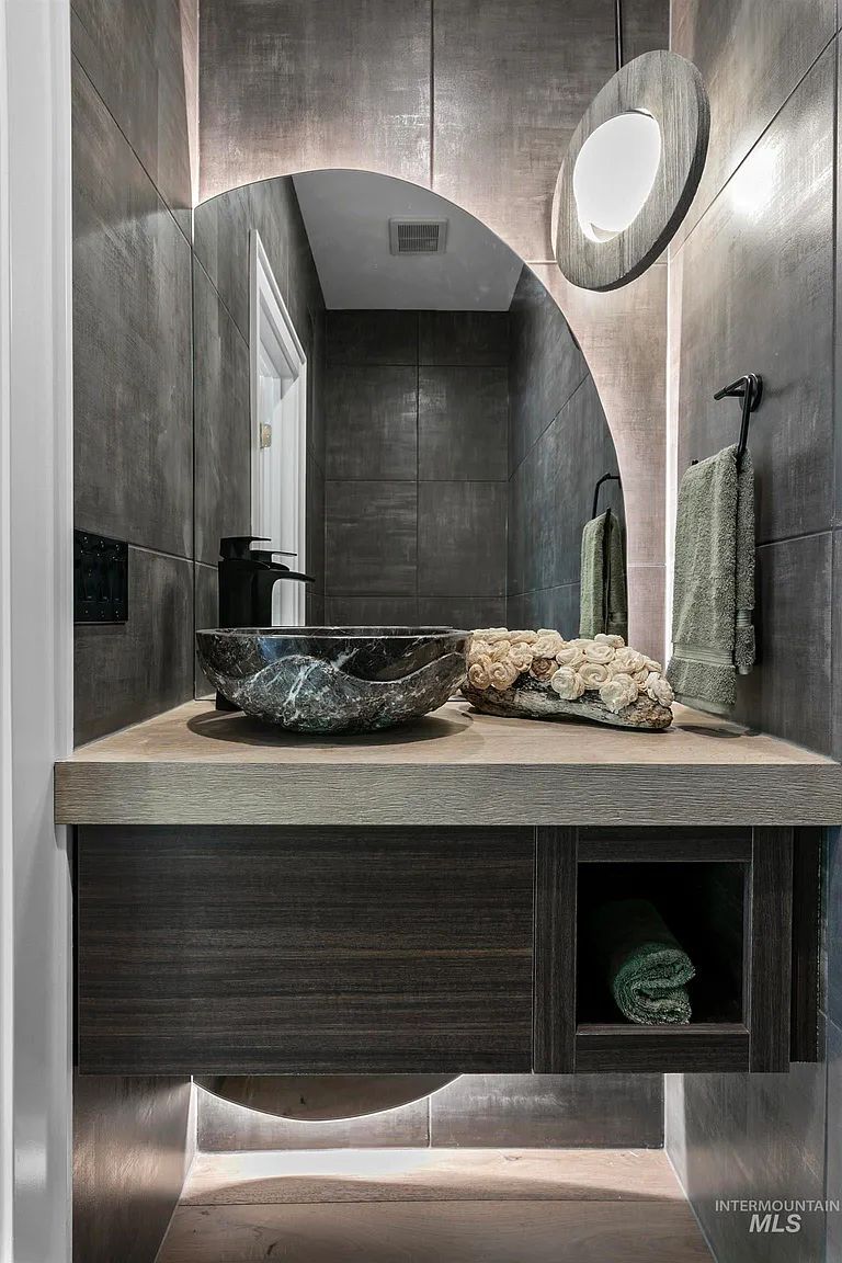 A bathroom with a sink , mirror , and towels.