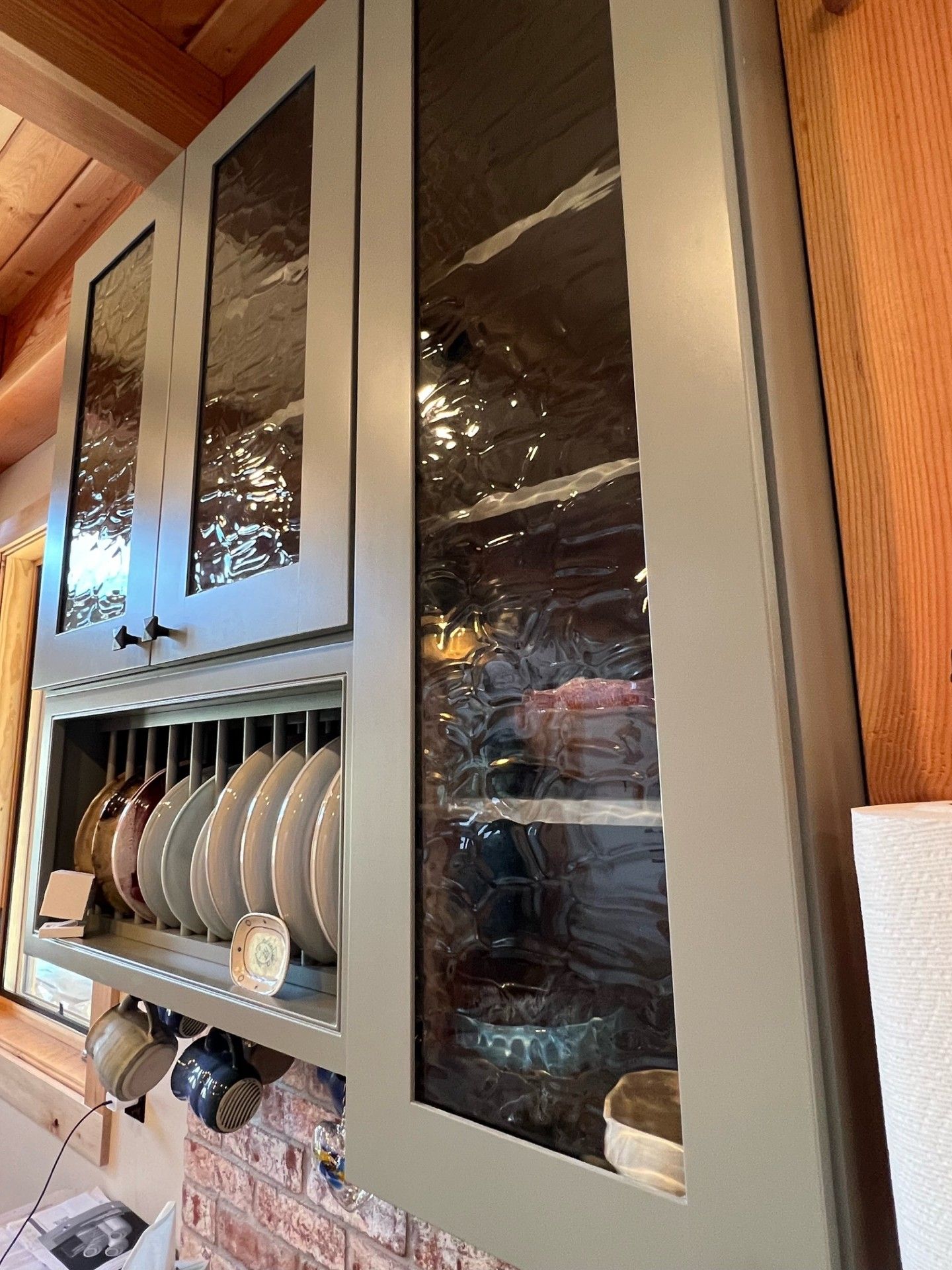 A kitchen cabinet with glass doors filled with dishes and cups.