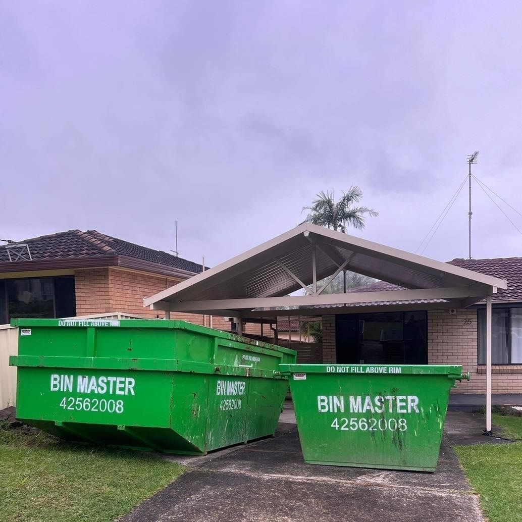 Two green bins are parked in front of a house.
