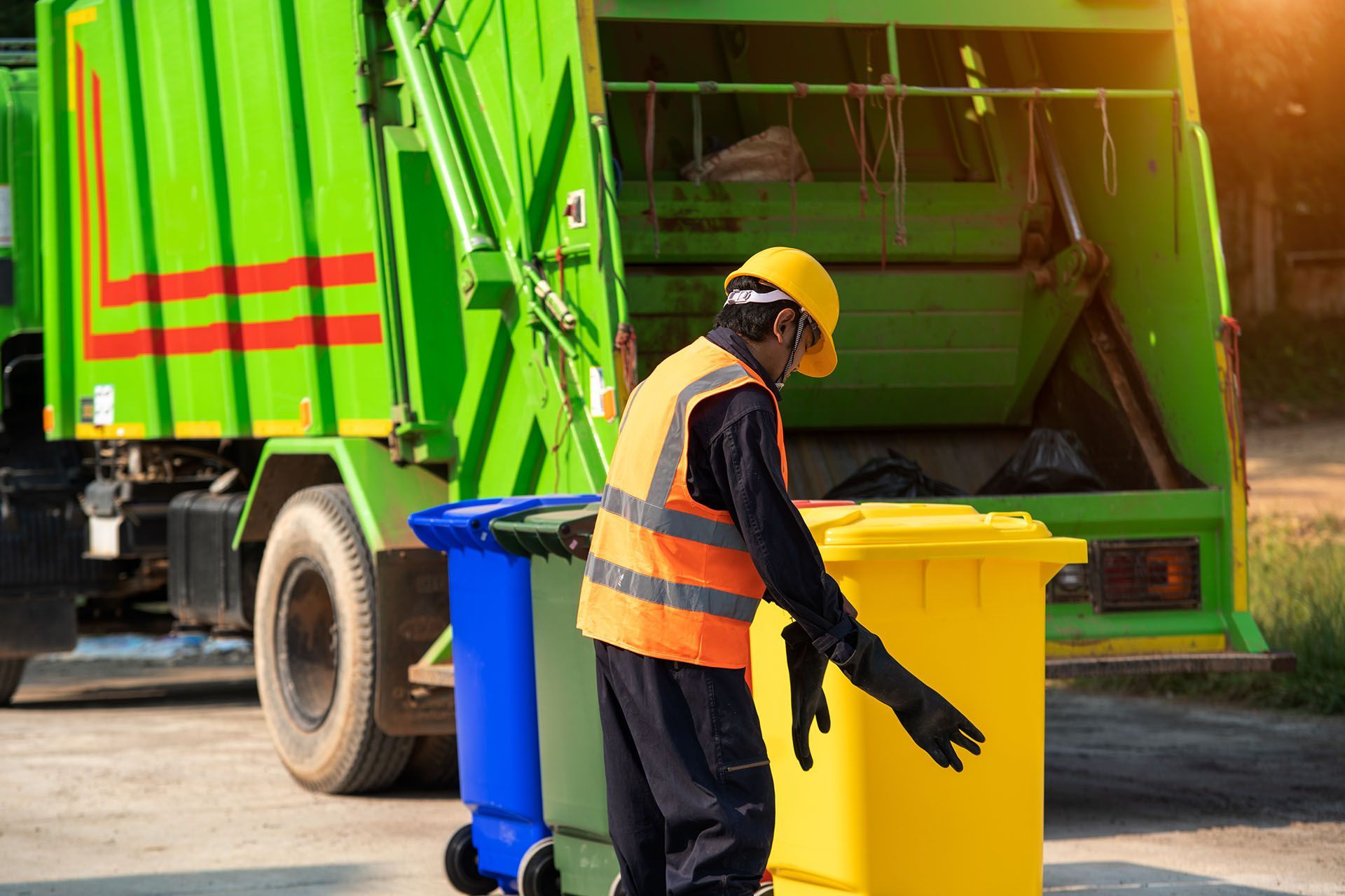 A man is loading garbage into a garbage truck.