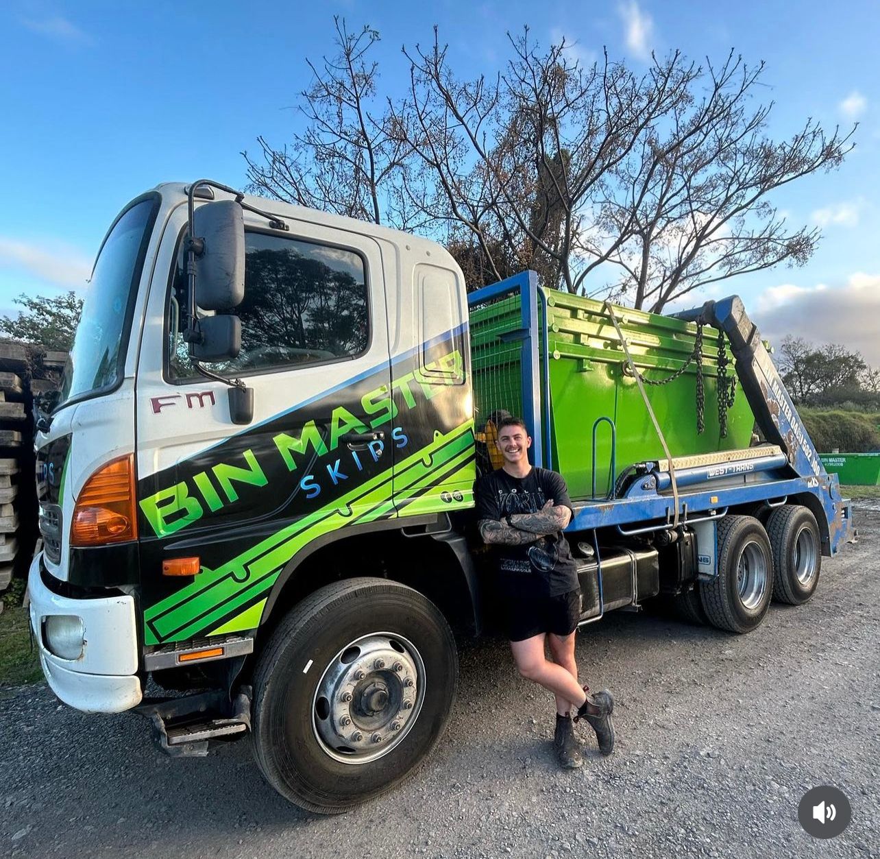 A man is standing in front of a Bin Masters dump truck.