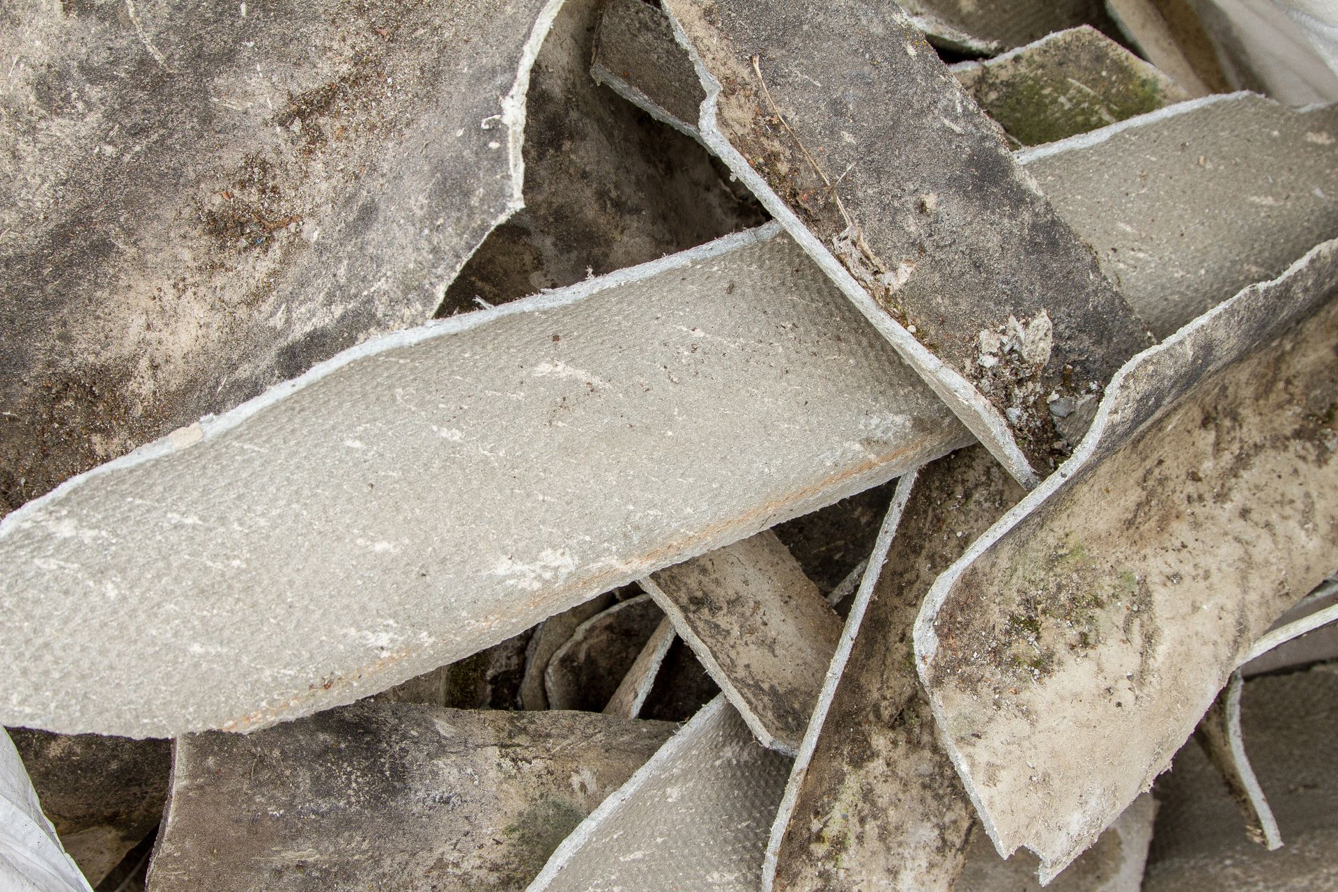 Pile of broken, gray, textured concrete pieces with white edges.