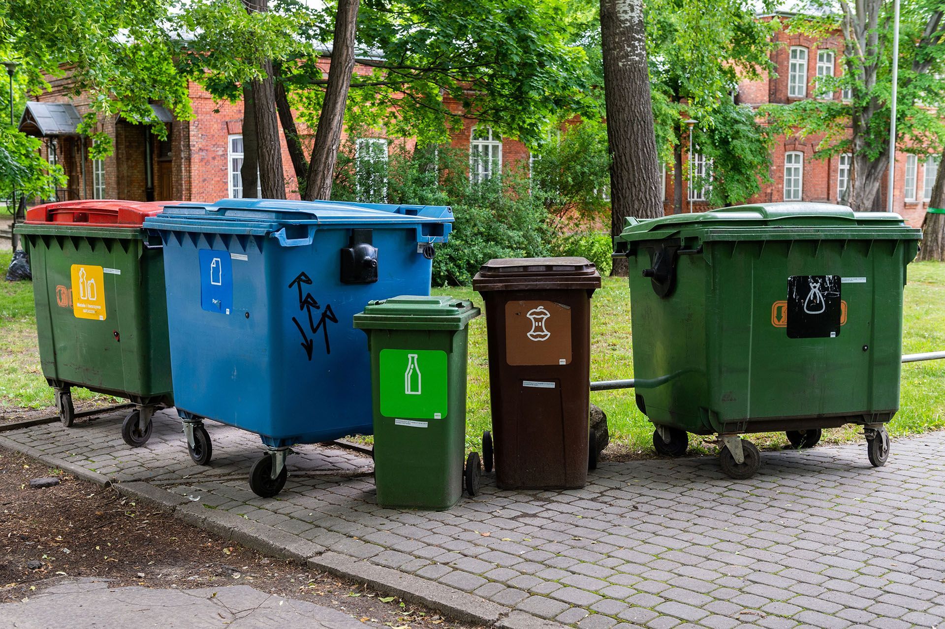 A group of trash cans are parked next to each other on a sidewalk.