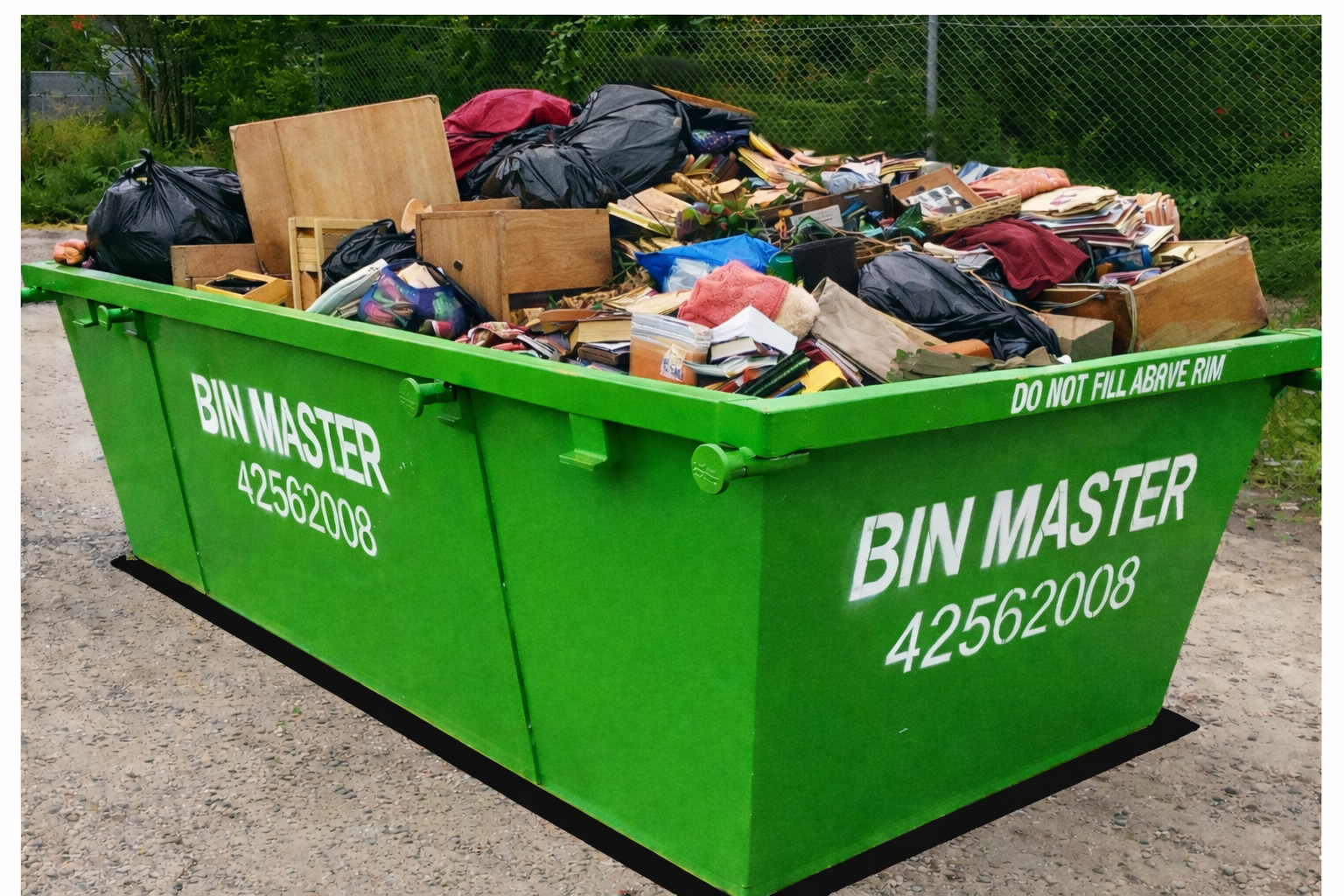 Green dumpster overflowing with trash on a grassy lawn.