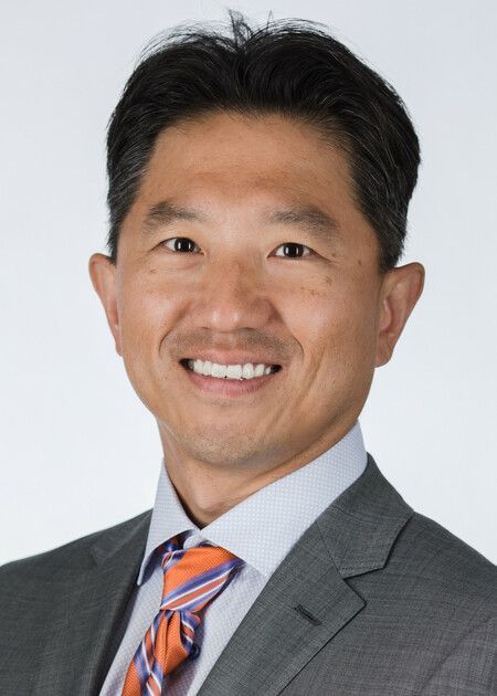 A smiling doctor in a lab coat with a stethoscope around his neck.