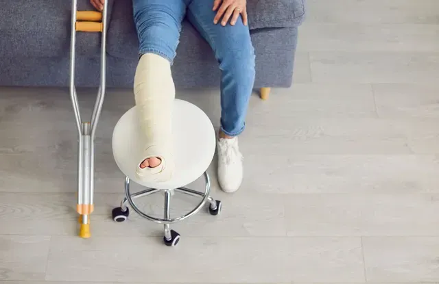 Person with leg cast sits, crutches next to them.