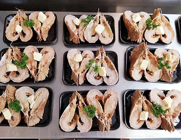 Lobster Halves with Butter and Parsley on Black Trays — Glenmore Seafoods In Park Avenue, QLD