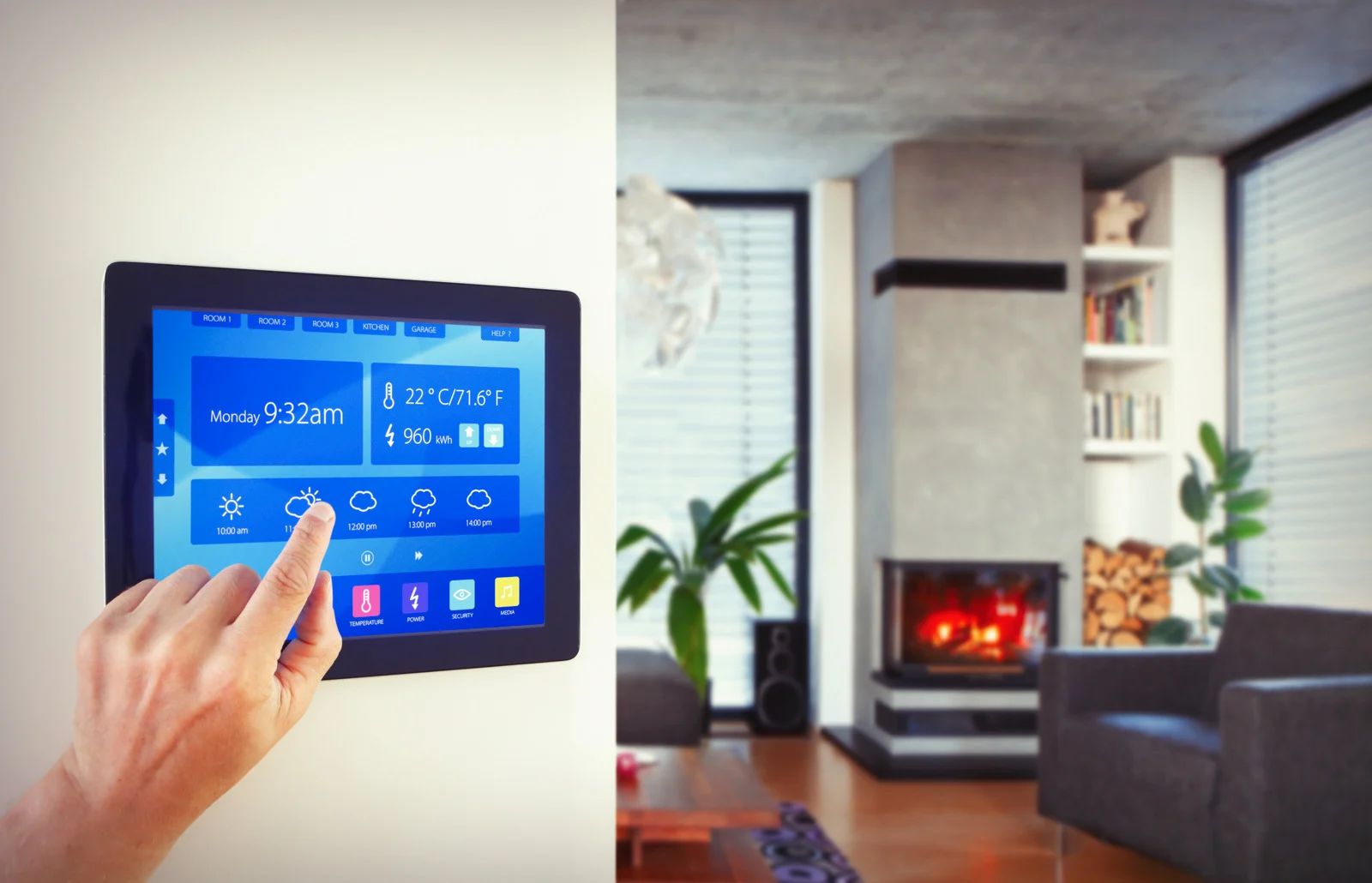 A hand touching a wall-mounted tablet displaying smart home controls in a living room with a fireplace.