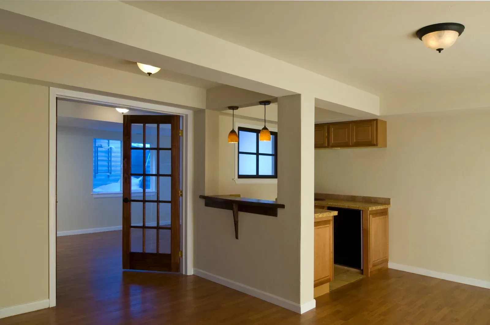 An empty room with a french door leading to a kitchen