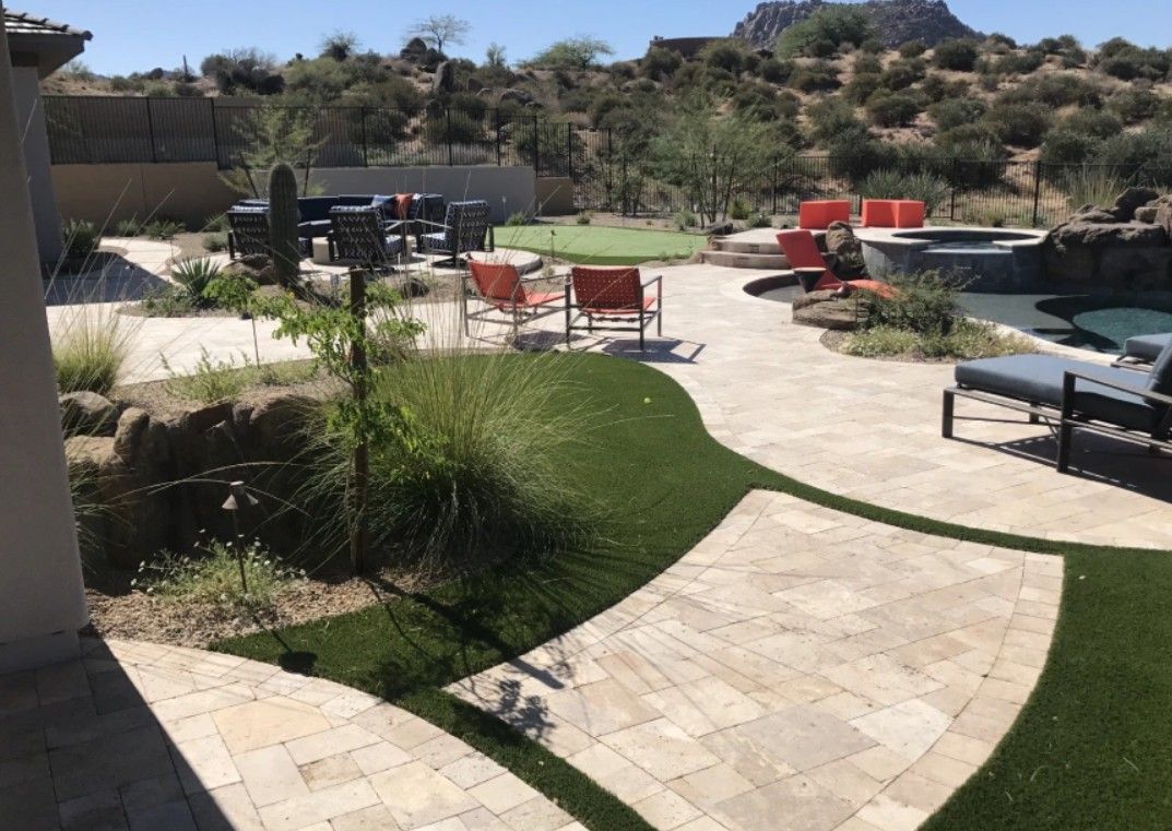 A large backyard with a patio , chairs , and a pool.
