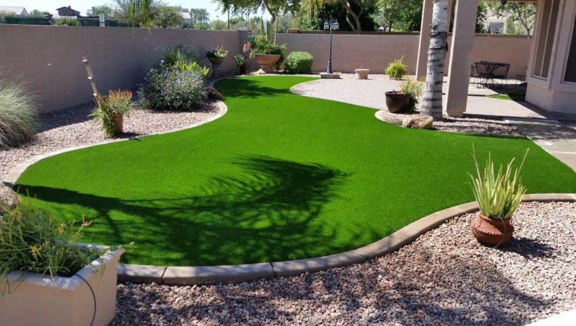 A backyard with a lush green lawn and potted plants.