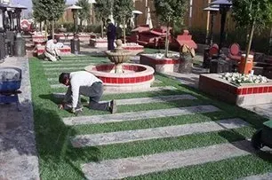 A man is kneeling on the grass in a park.