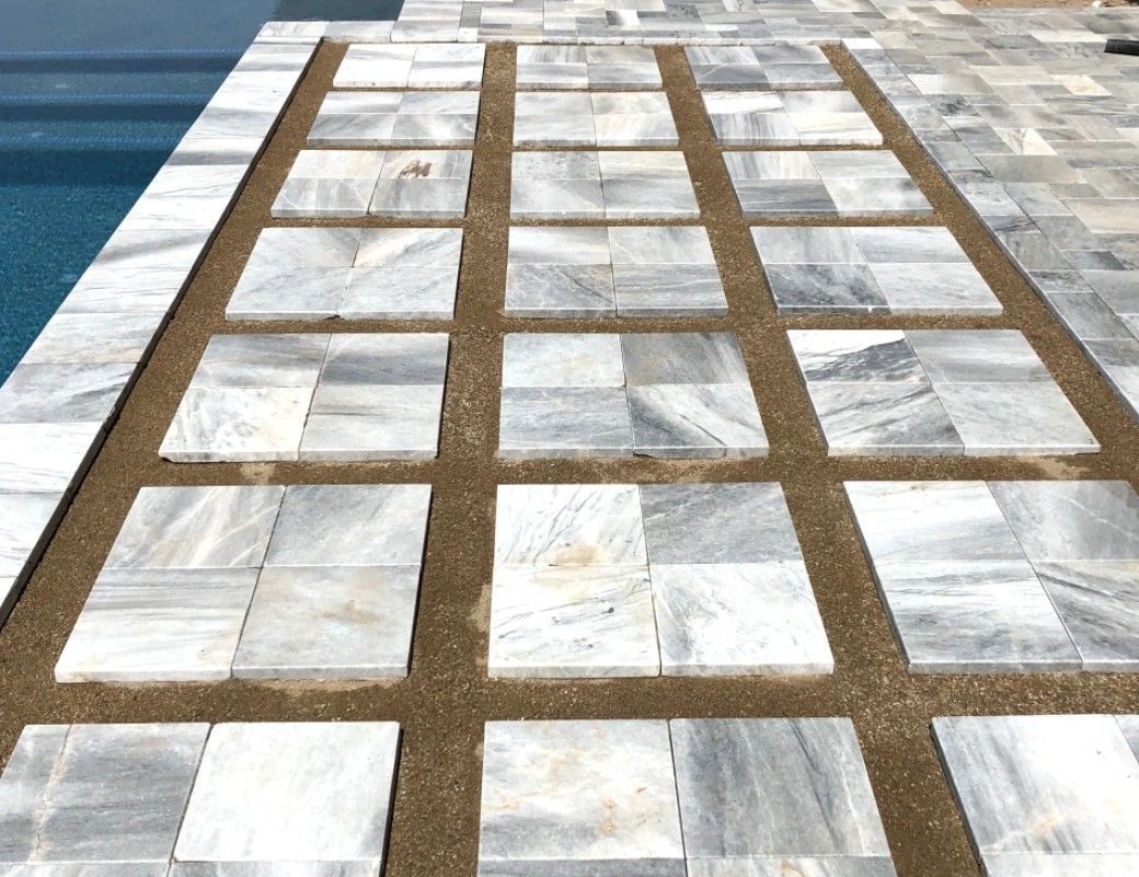 A walkway made of tiles next to a pool.
