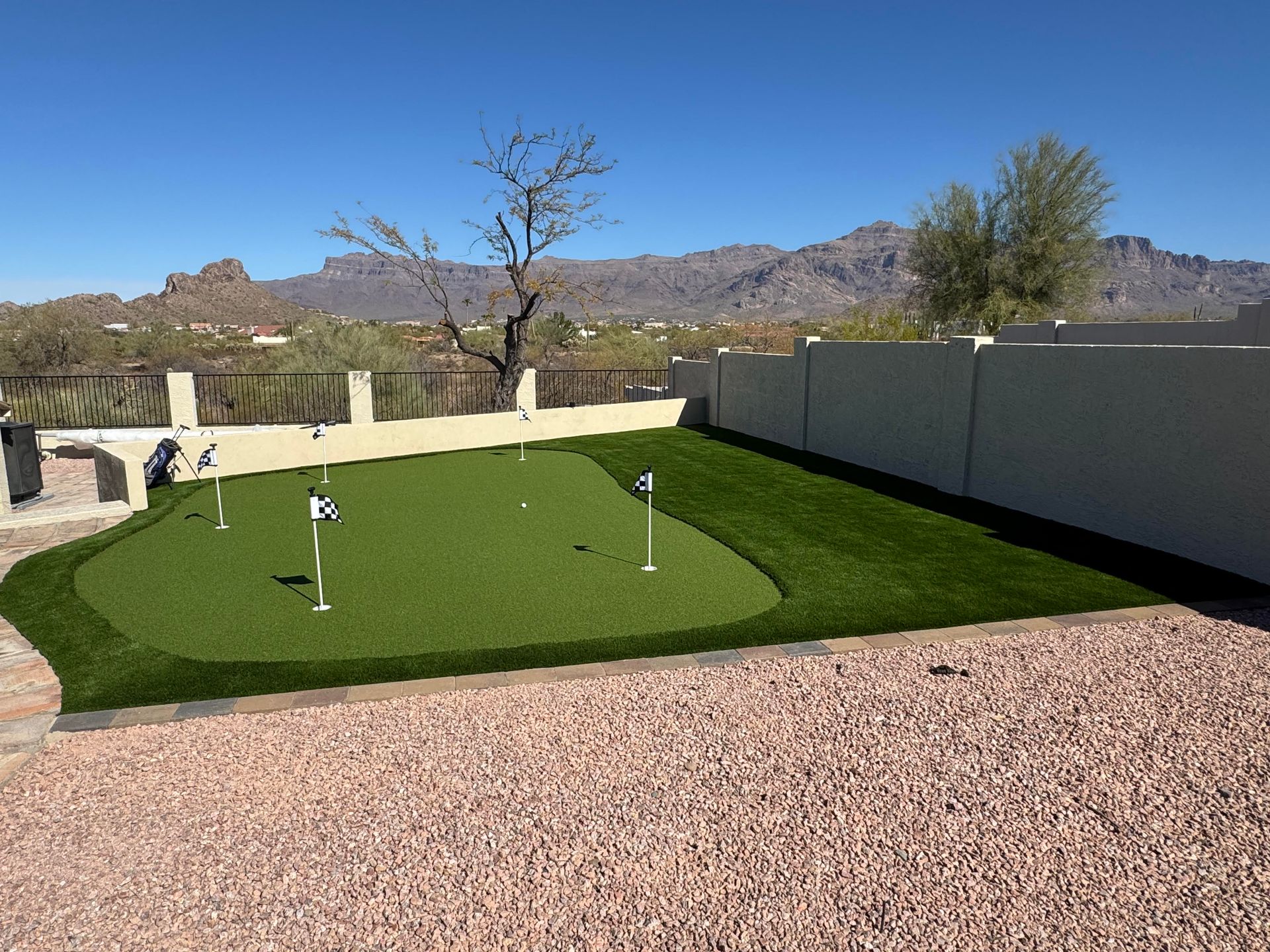 A putting green in the backyard of a house with mountains in the background.