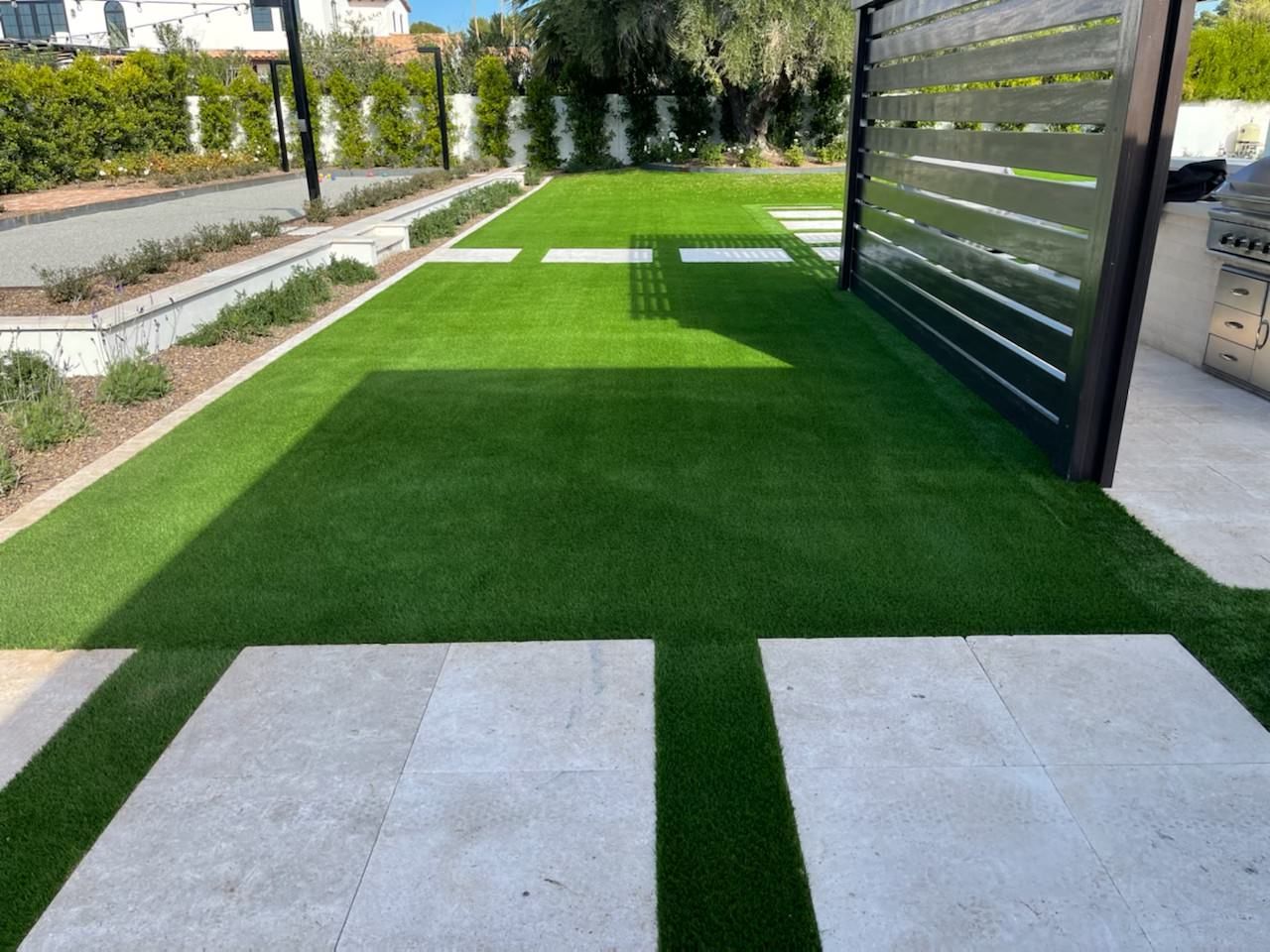 A lawn with a fence and a walkway leading to it.