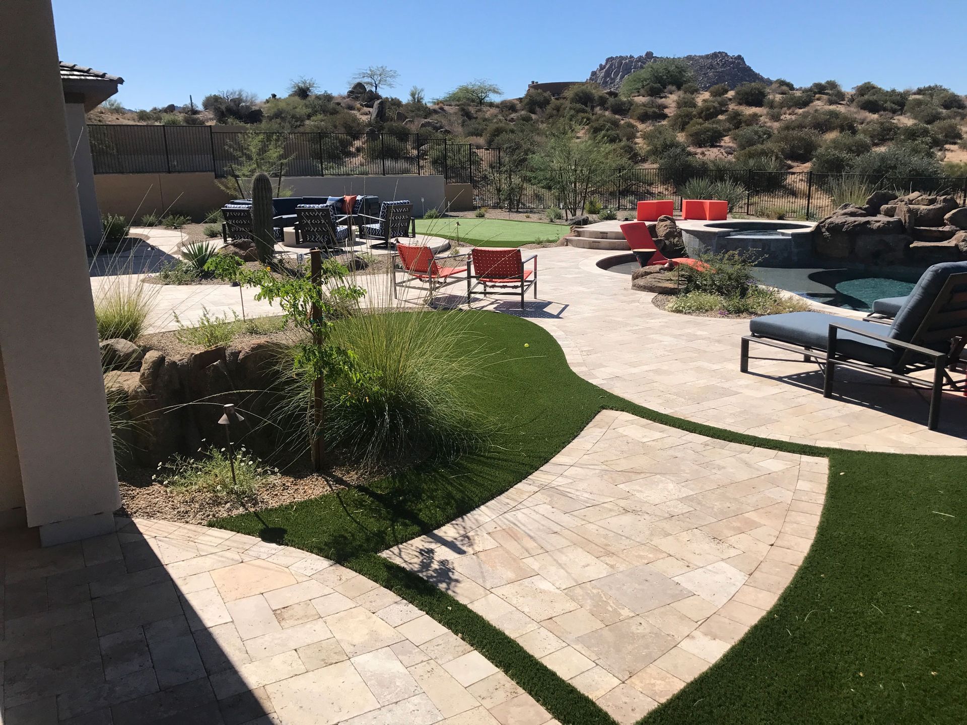 A backyard with a patio , chairs , and a pool.