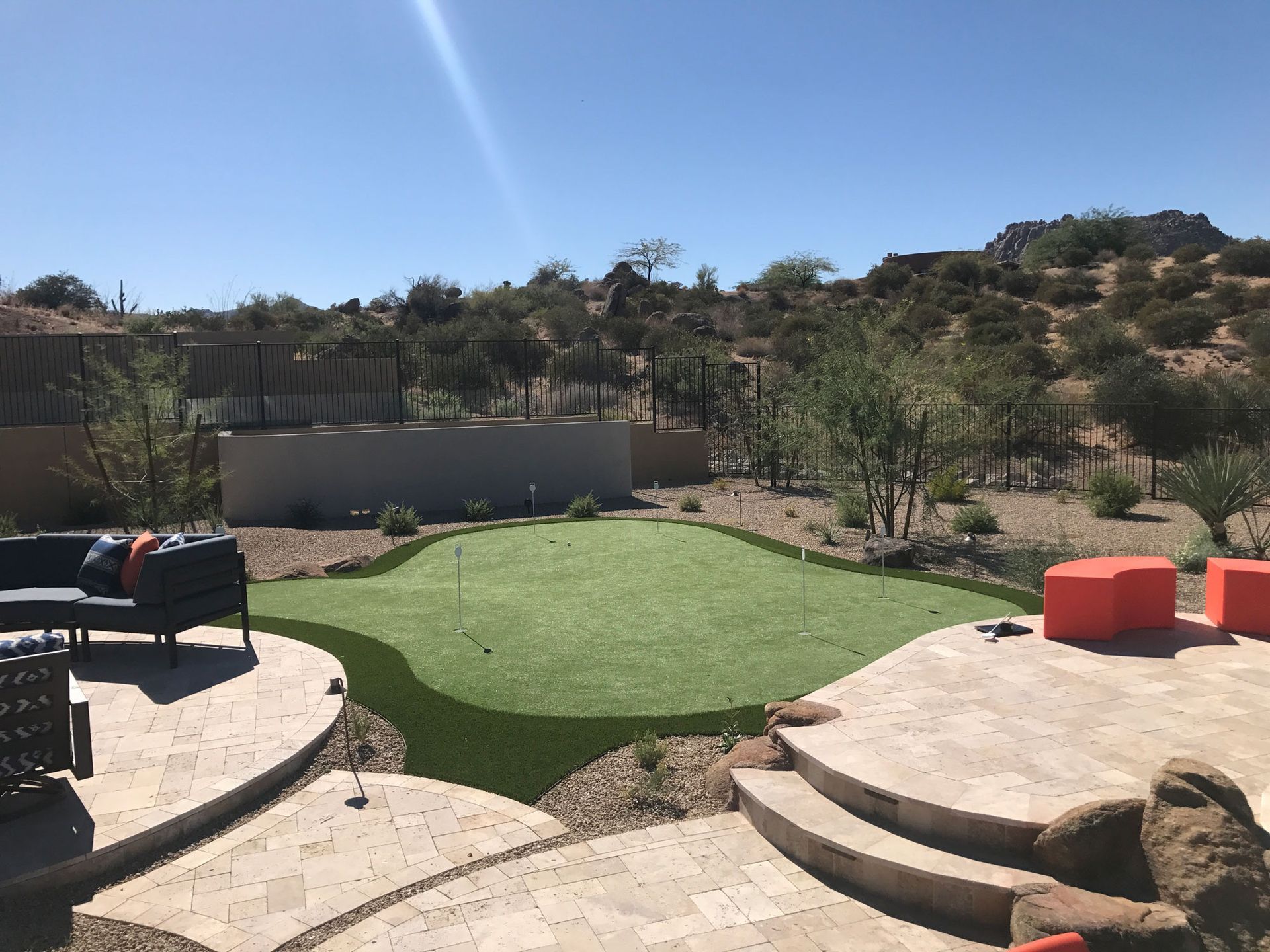 There is a putting green in the middle of the backyard.