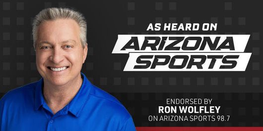 A smiling man in blue shirt, endorsed by Ron Wolfley on Arizona Sports 98.7.