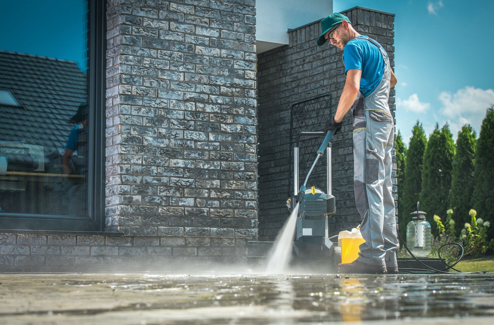 a man is cleaning a driveway with a high pressure washer .