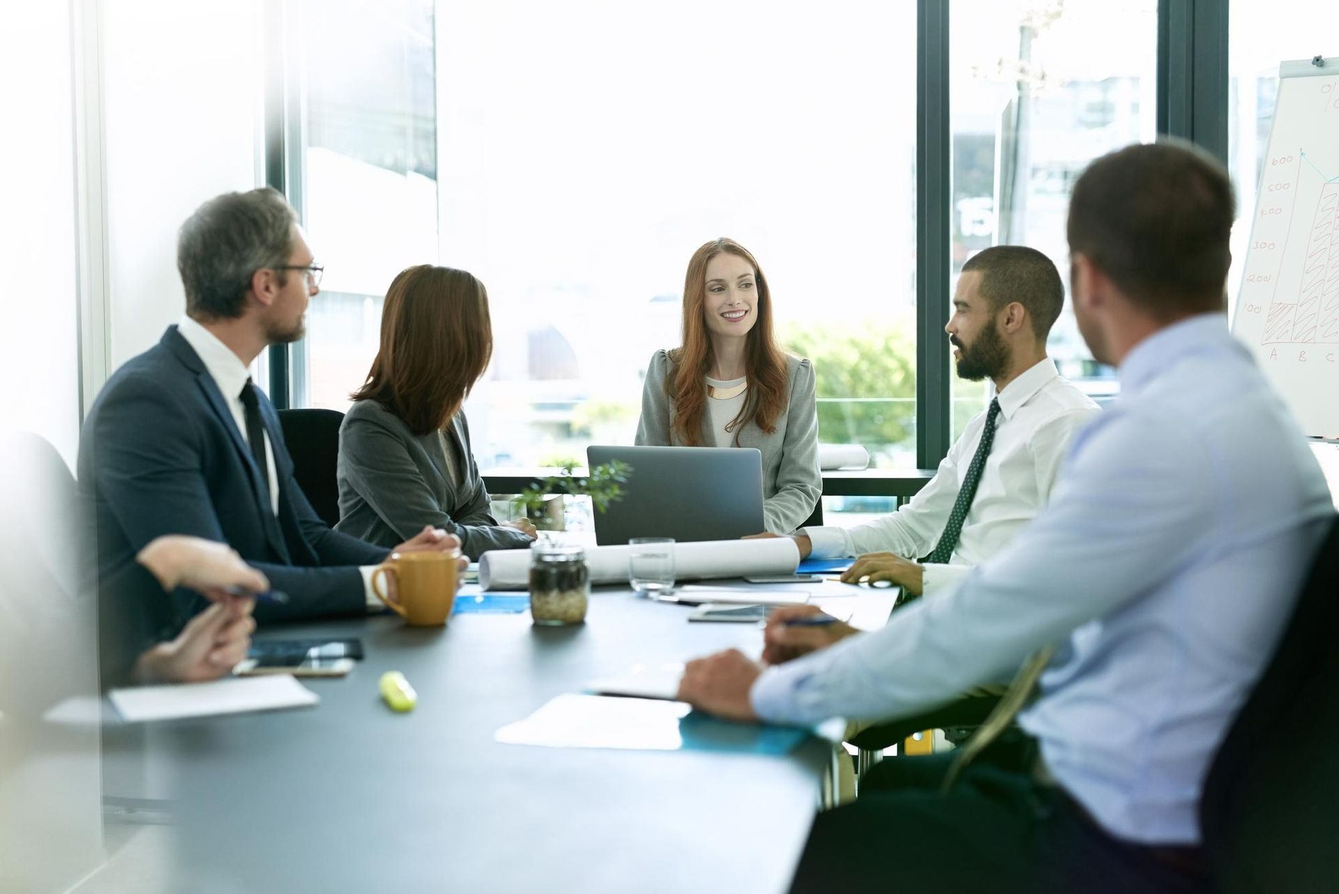Business meeting with diverse group seated around a table, discussing and working.